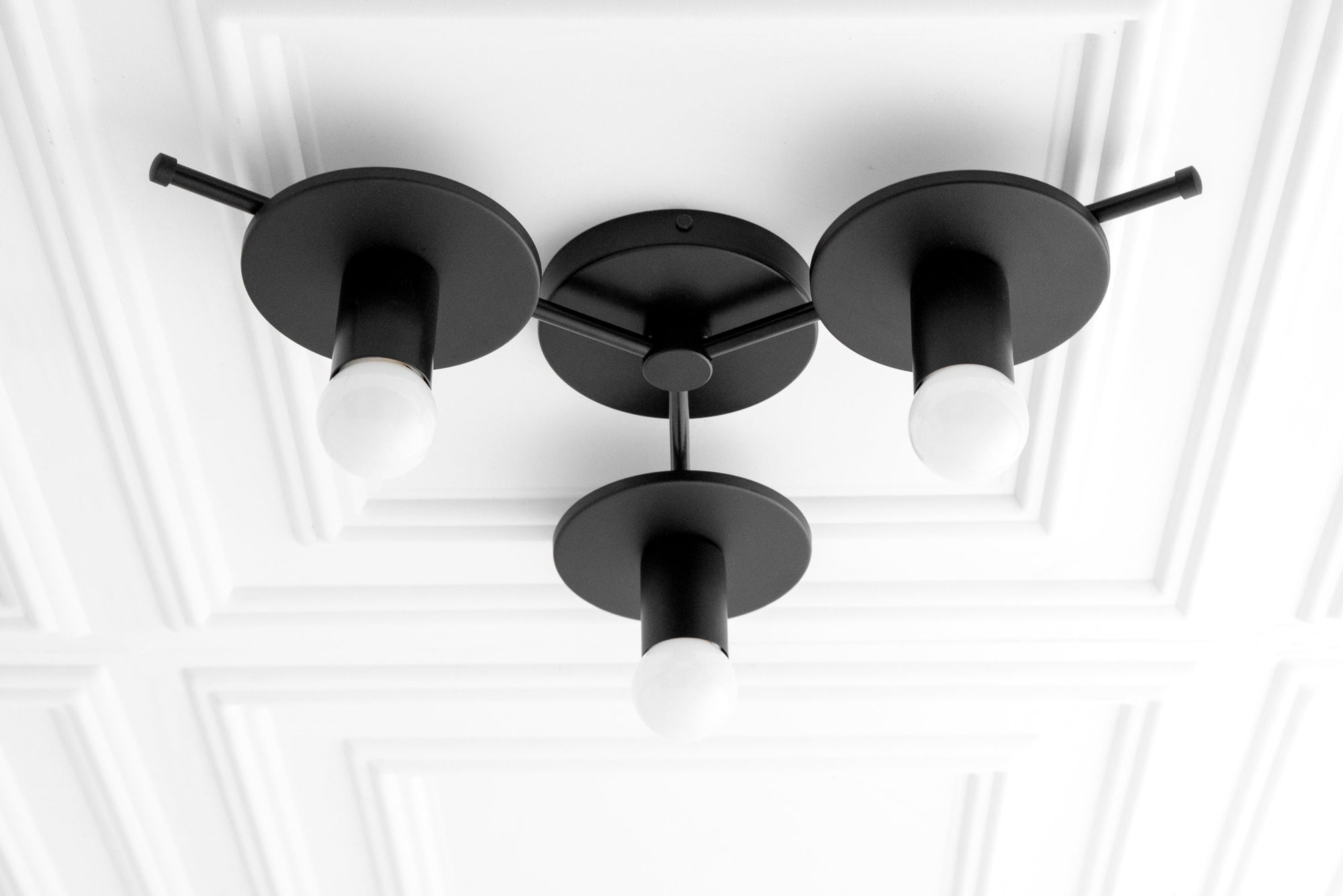 Black flush mount ceiling light with three exposed white bulbs arranged in a triangular mid-century modern design. - CHANDELIER MODEL NO. 9526