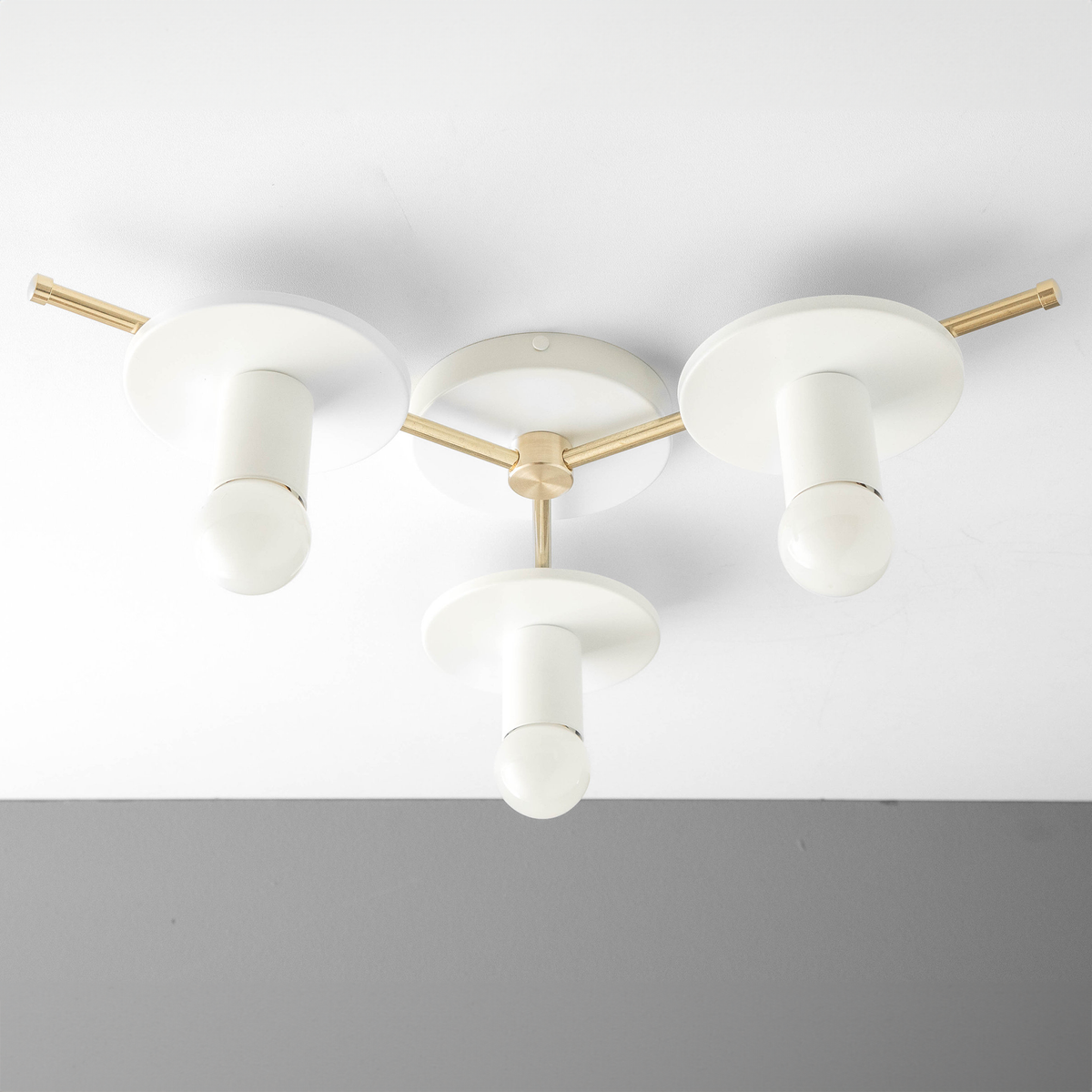 Mid-century modern flush mount chandelier with three white bare bulb sockets and raw brass arms. - CHANDELIER MODEL NO. 9526