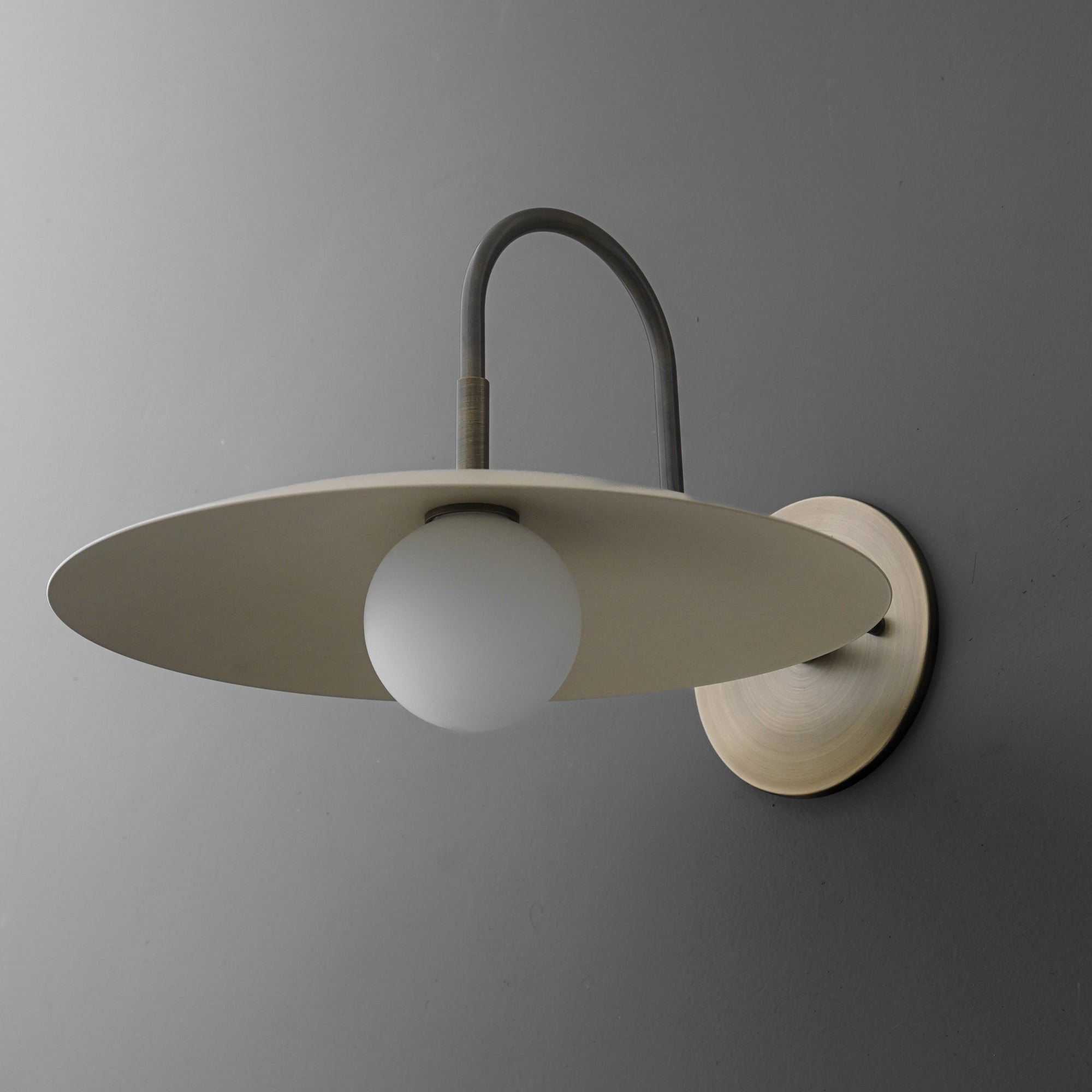 Antique brass wall sconce with cream flat disc shade and frosted globe bulb. - SCONCE MODEL NO. 9171