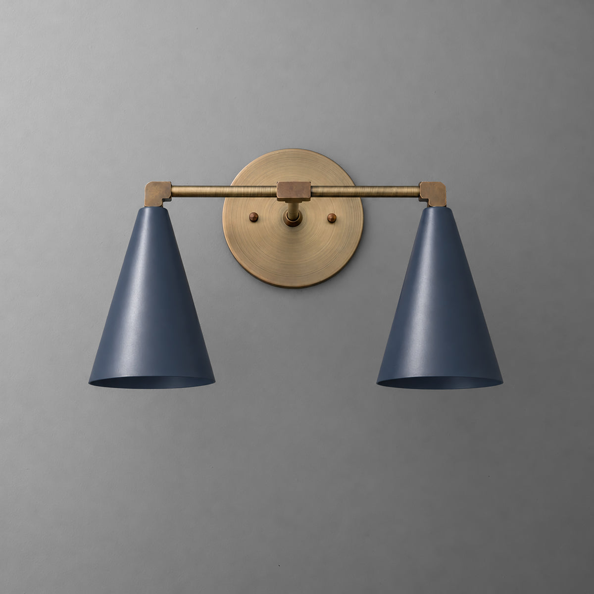 Two-light vanity light in Antique Brass with Coal Blue cone shades on a straight arm and a round wall plate. - VANITY LIGHT MODEL NO. 1184