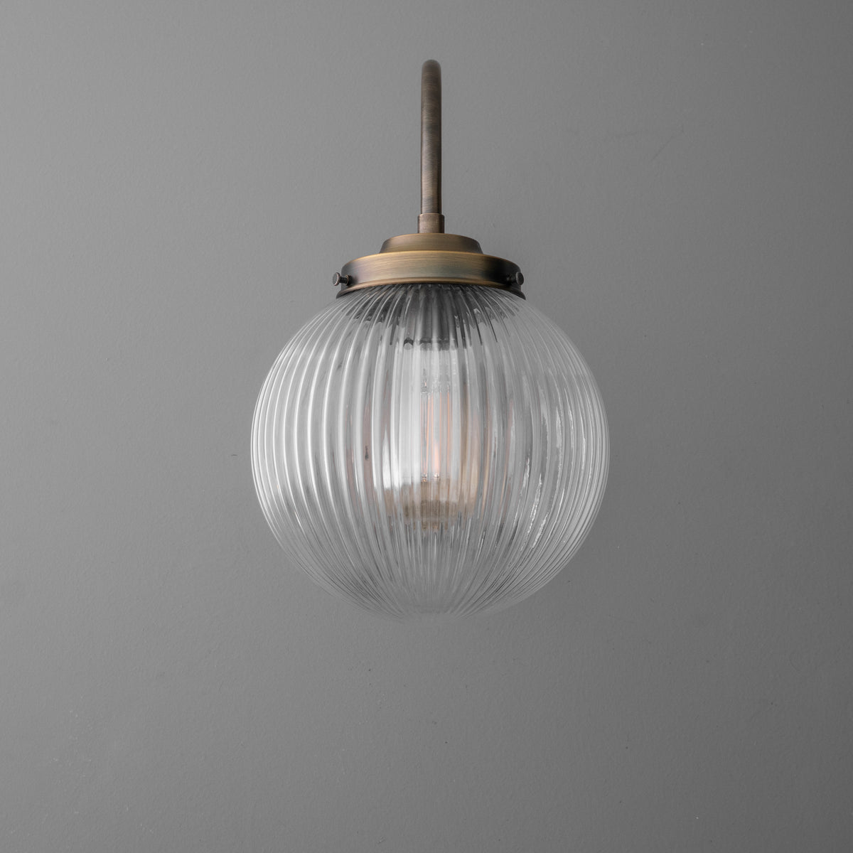 Wall sconce with ribbed clear glass globe and antique brass mounting hardware. - SCONCE MODEL NO. 8763