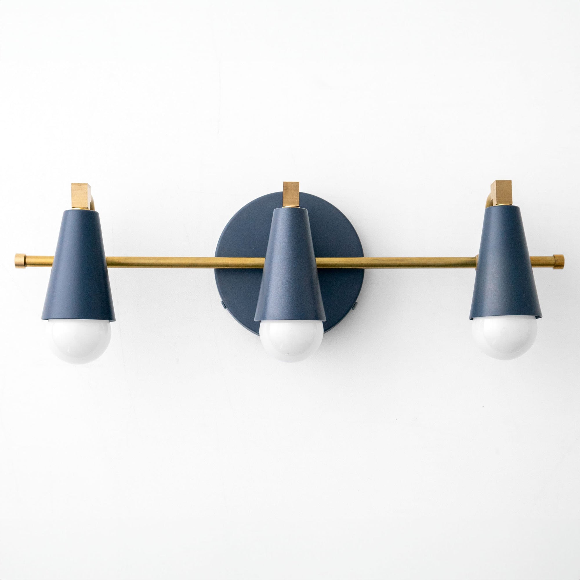 Three-light vanity fixture with matte blue conical shades, brass accents, and white bulbs on round backplate. - VANITY LIGHT MODEL NO. 8084