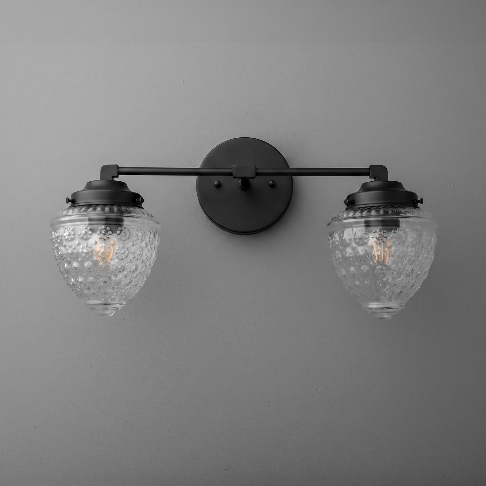 Black metal double vanity light with textured clear glass shades and vintage-style bulbs. - VANITY LIGHT MODEL NO. 1155