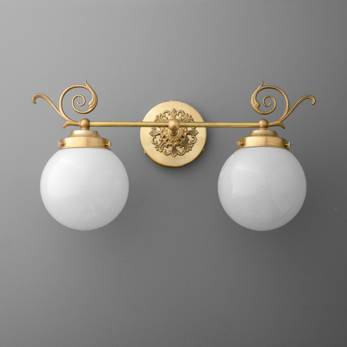 Two-bulb vanity light with frosted glass globes and ornate gold metal fixture with scroll detailing. - VANITY LIGHT MODEL NO. 1135