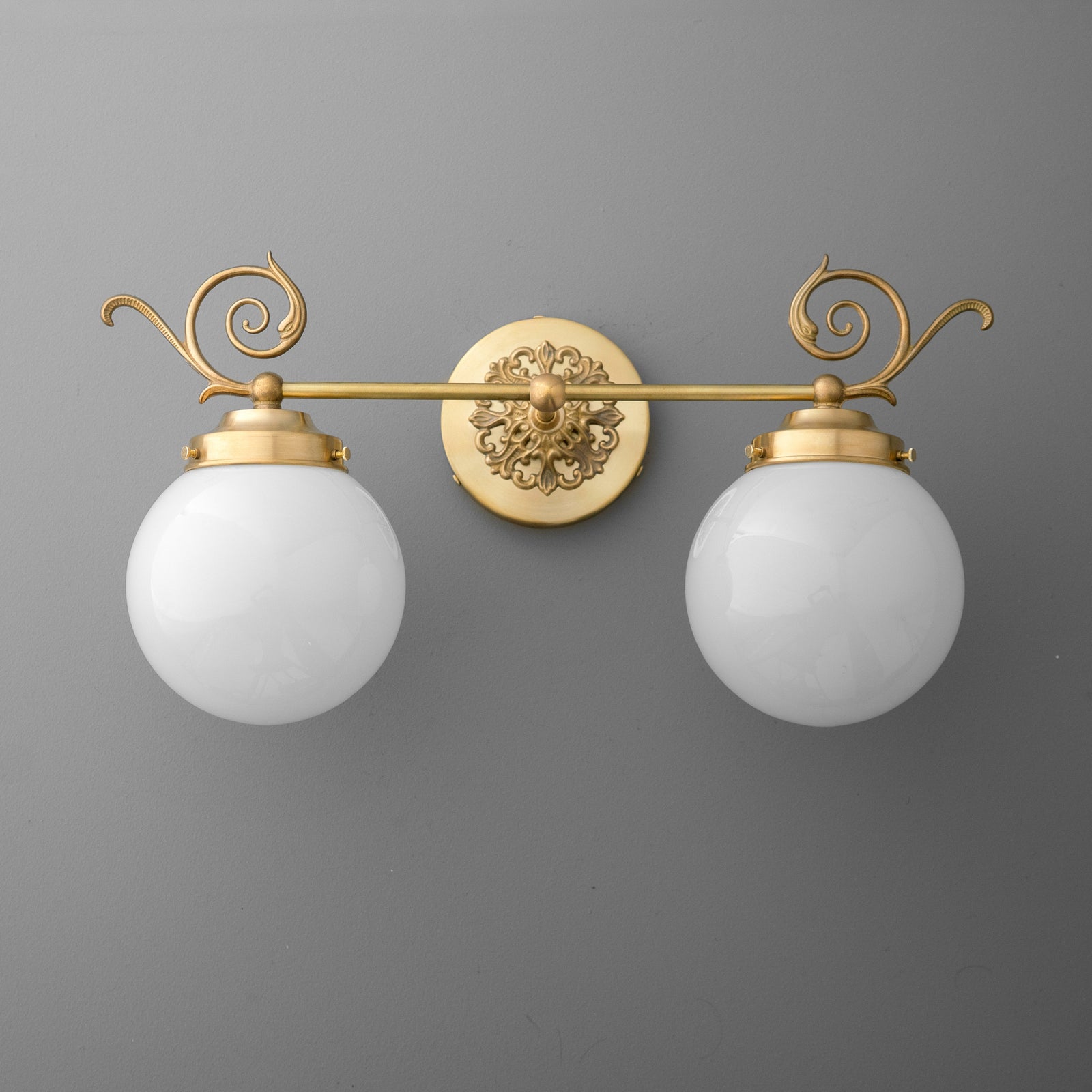 Two-bulb vanity light with frosted glass globes and ornate gold metal fixture with scroll detailing. - VANITY LIGHT MODEL NO. 1135