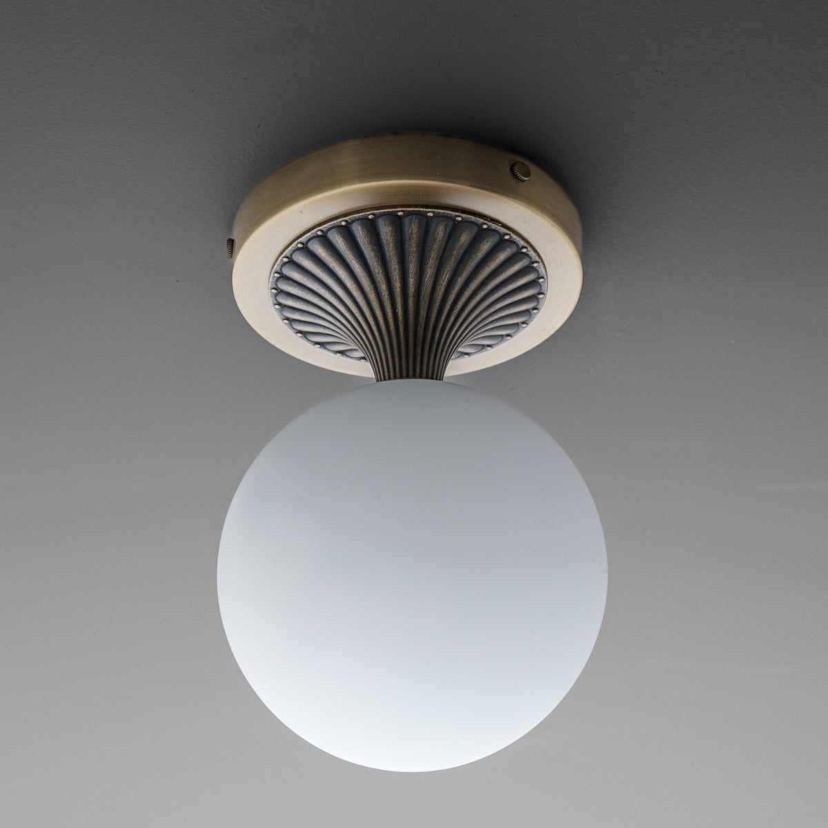 Wall sconce with matte white glass globe and antique brass circular base featuring black ribbed detailing. - SCONCE MODEL NO. 5363