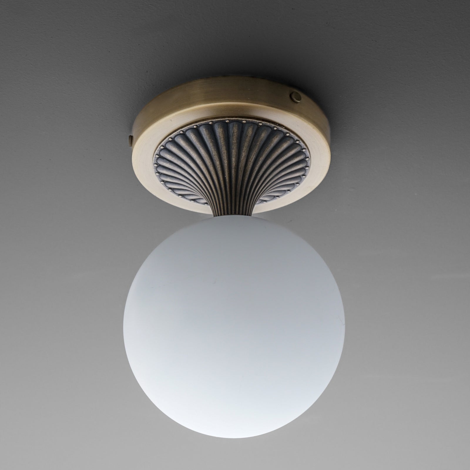 Wall sconce with matte white glass globe and antique brass circular base featuring black ribbed detailing. - SCONCE MODEL NO. 5363