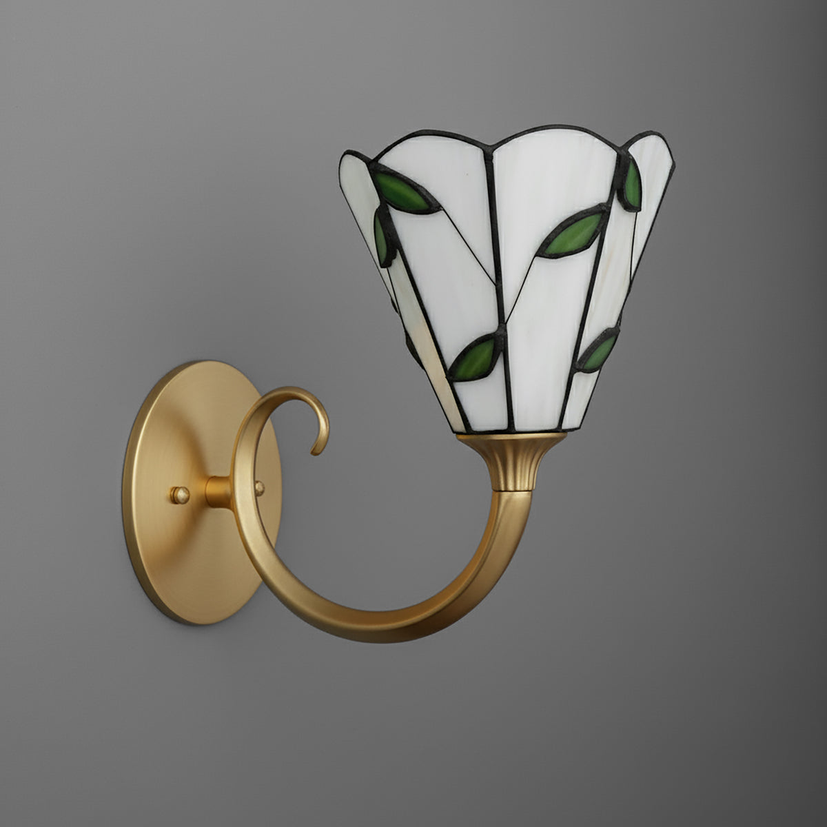 Brass wall sconce with curved arm and stained glass shade featuring white panels and green leaf accents. - SCONCE MODEL NO. 1056