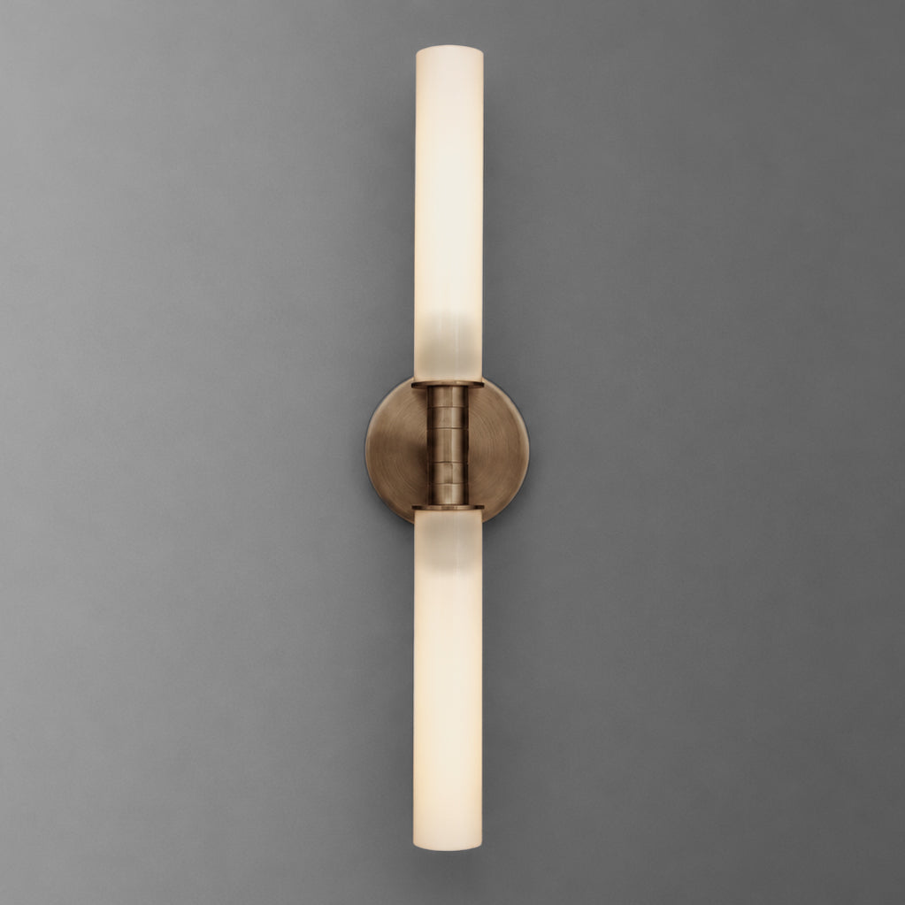 Vertical vanity light in Antique Brass with long cylinder shades pointing up and down from a round wall plate. - VANITY LIGHT MODEL NO. 1183