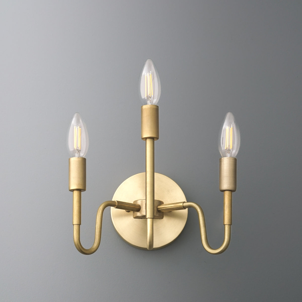 Matte gold three-bulb wall sconce with curved arms and candle-style LED lights. - SCONCE MODEL NO. 2943