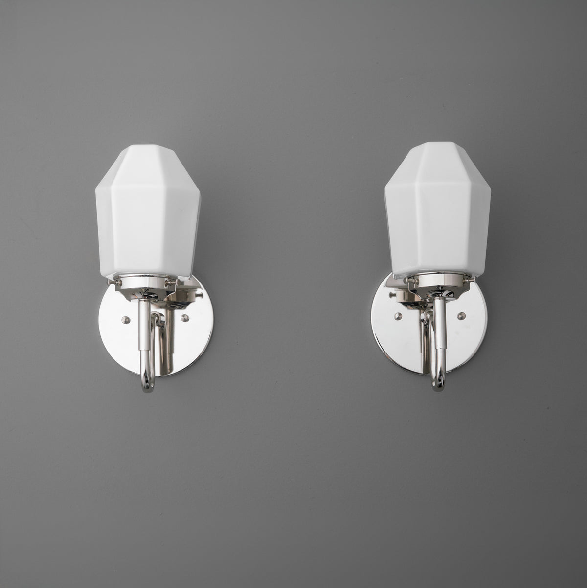 Pair of wall sconces with white geometric shades and polished chrome bases mounted on a gray wall. - SCONCE MODEL NO. 1038