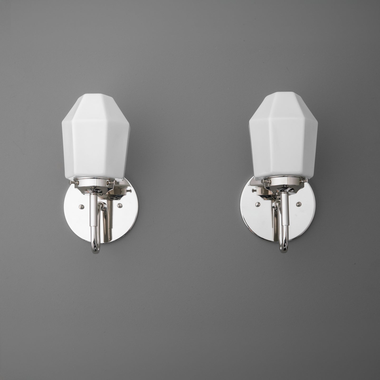Pair of wall sconces with white geometric shades and polished chrome bases mounted on a gray wall. - SCONCE MODEL NO. 1038
