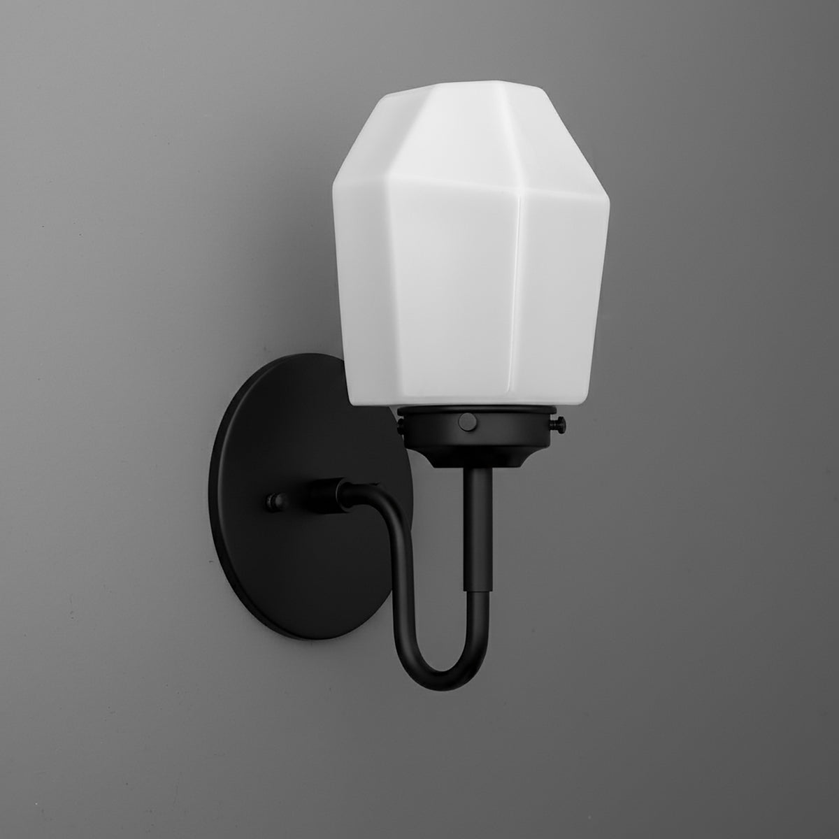 Black metal wall sconce with curved arm and white geometric faceted glass shade. - SCONCE MODEL NO. 1038