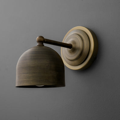 Wall-mounted antique brass sconce with dome-shaped shade and round backplate on gray wall. - SCONCE MODEL NO. 6649
