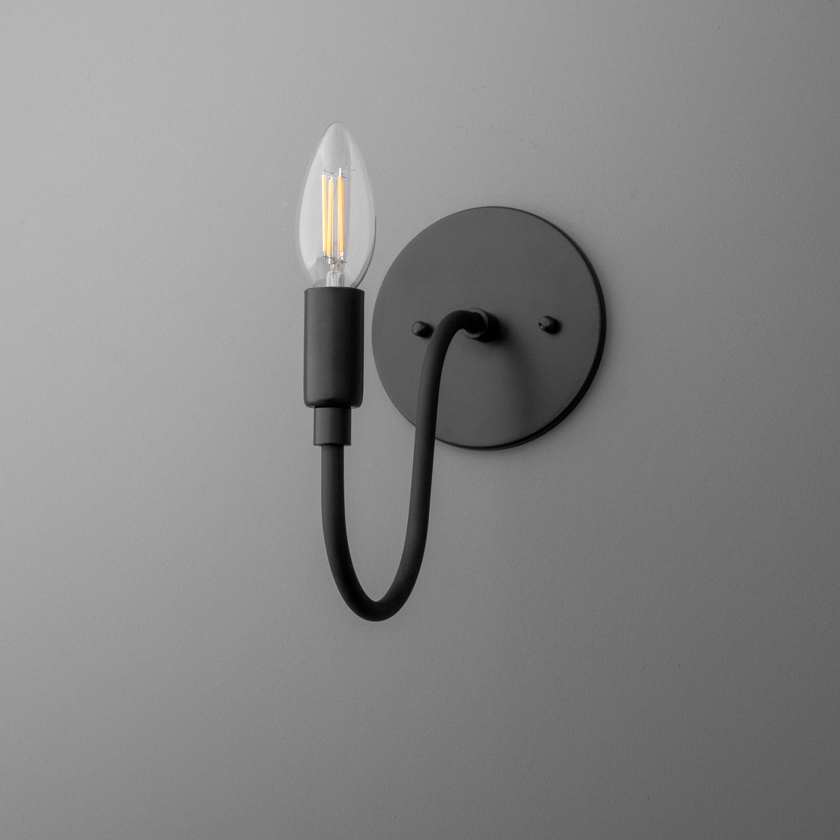 Matte black metal wall sconce with curved arm and exposed vintage-style filament bulb. - SCONCE MODEL NO. 7321