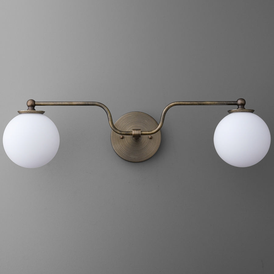 Wall-mounted vanity light with two white glass globe shades and a brushed brass finish frame. - VANITY LIGHT MODEL NO. 1153