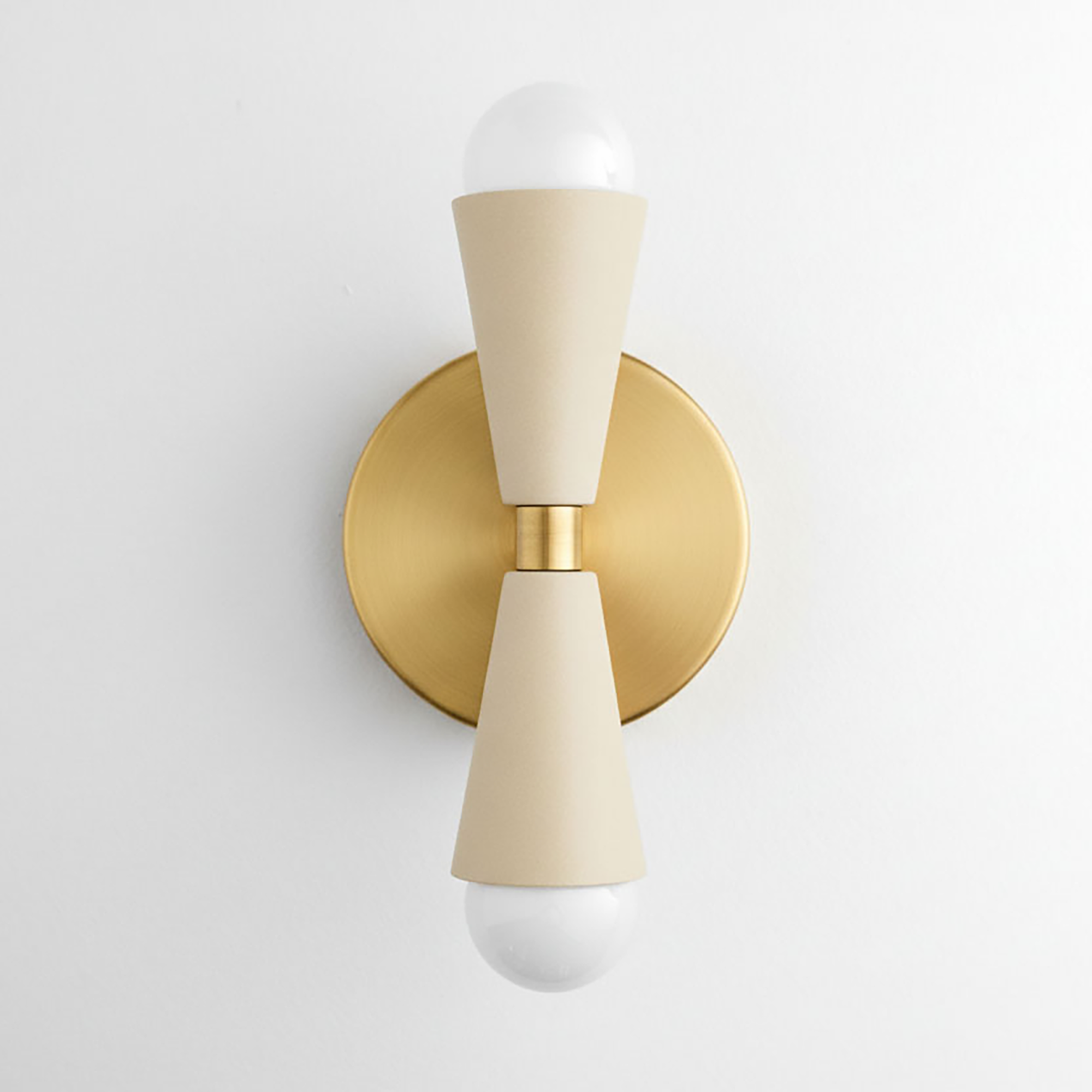 Wall sconce with antique brass round backplate and cream tapered arms holding exposed bulbs up and down. - SCONCE MODEL NO. 4717