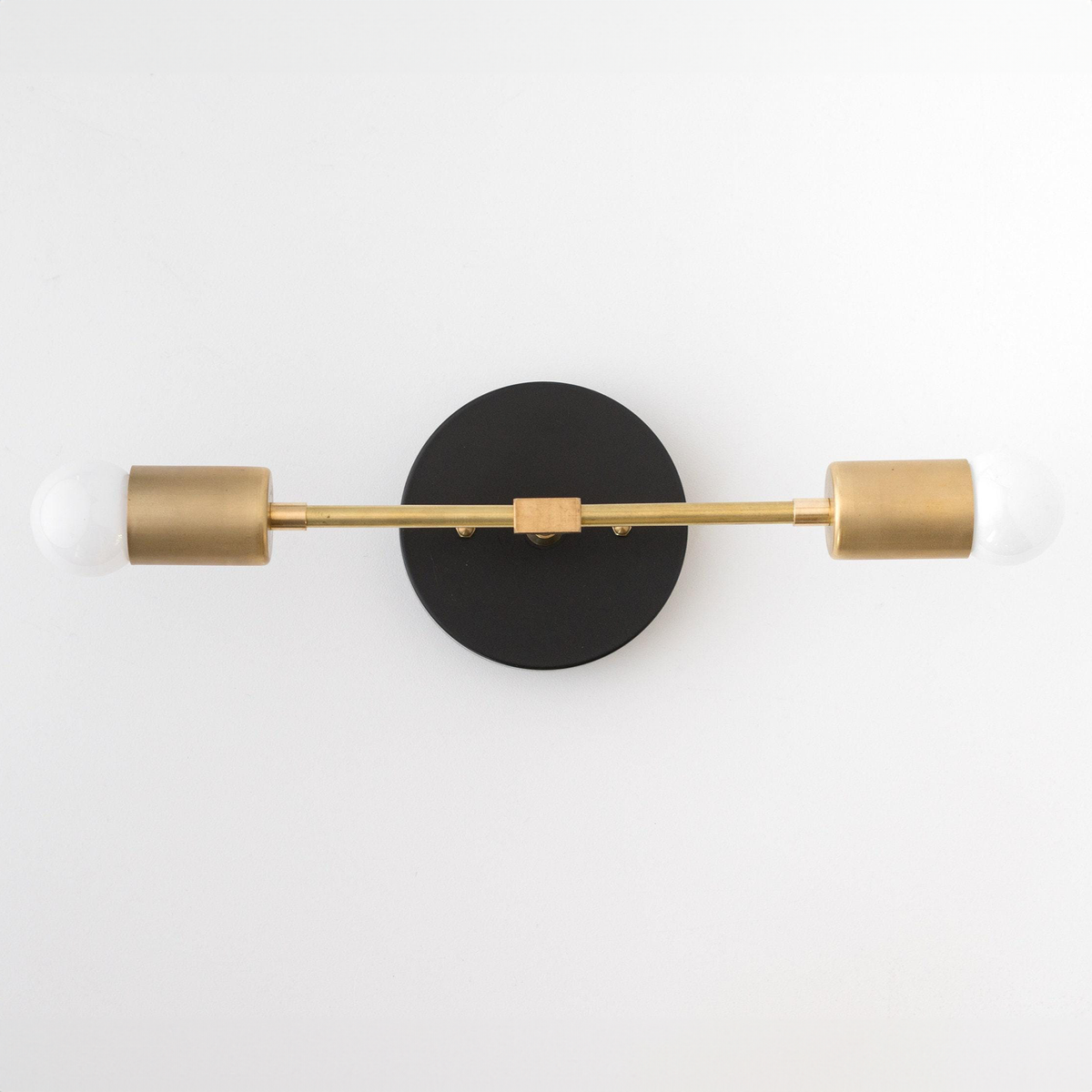 Mid-century modern 2-bulb vanity light with black round base and raw brass cylindrical sockets. - VANITY LIGHT MODEL NO. 5563