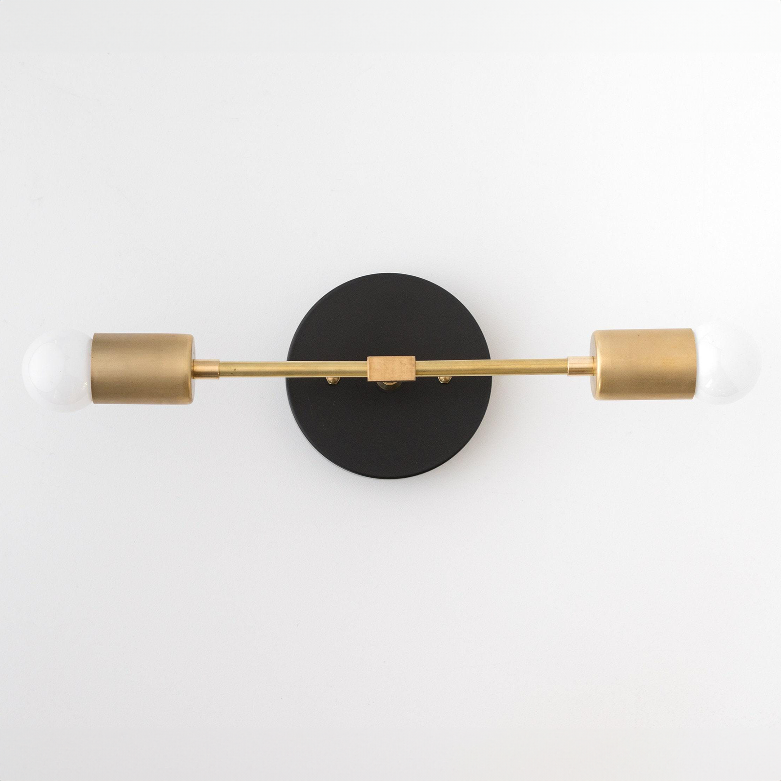 Mid-century modern 2-bulb vanity light with black round base and raw brass cylindrical sockets. - VANITY LIGHT MODEL NO. 5563