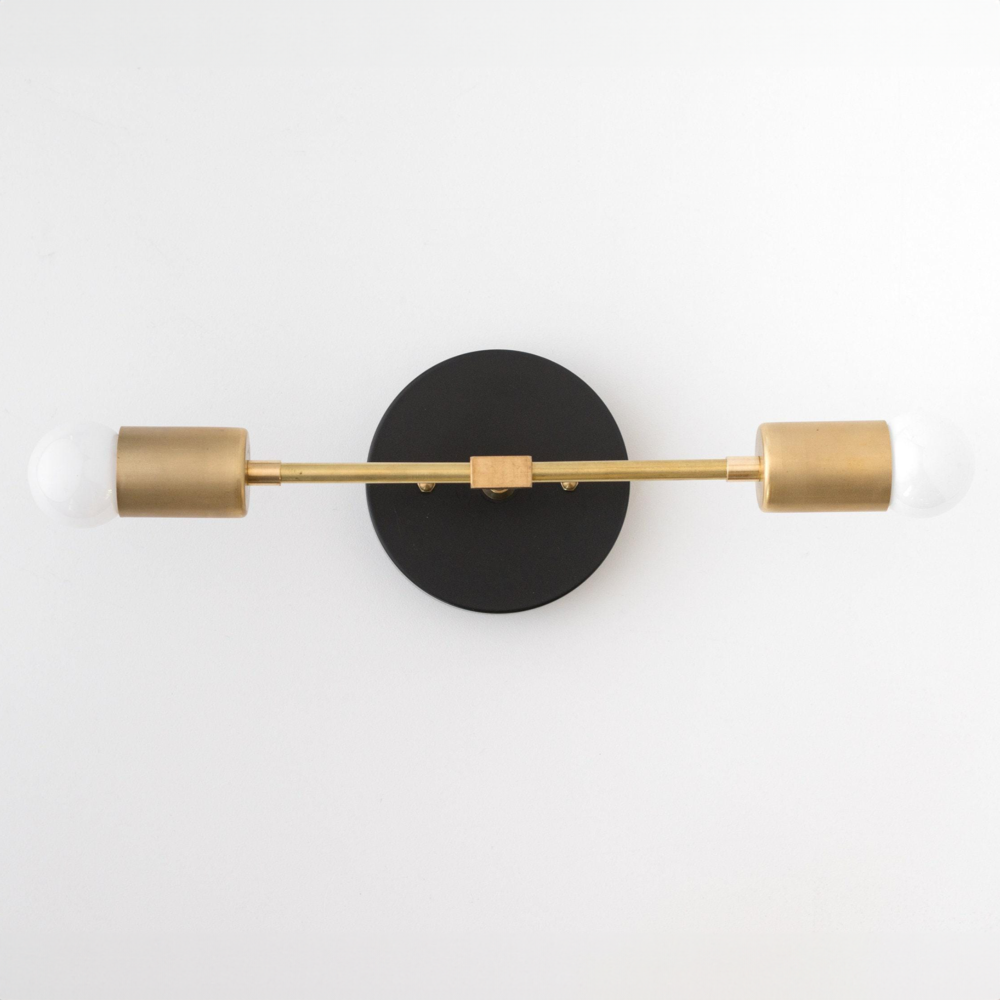 Mid-century modern 2-bulb vanity light with black round base and raw brass cylindrical sockets. - VANITY LIGHT MODEL NO. 5563