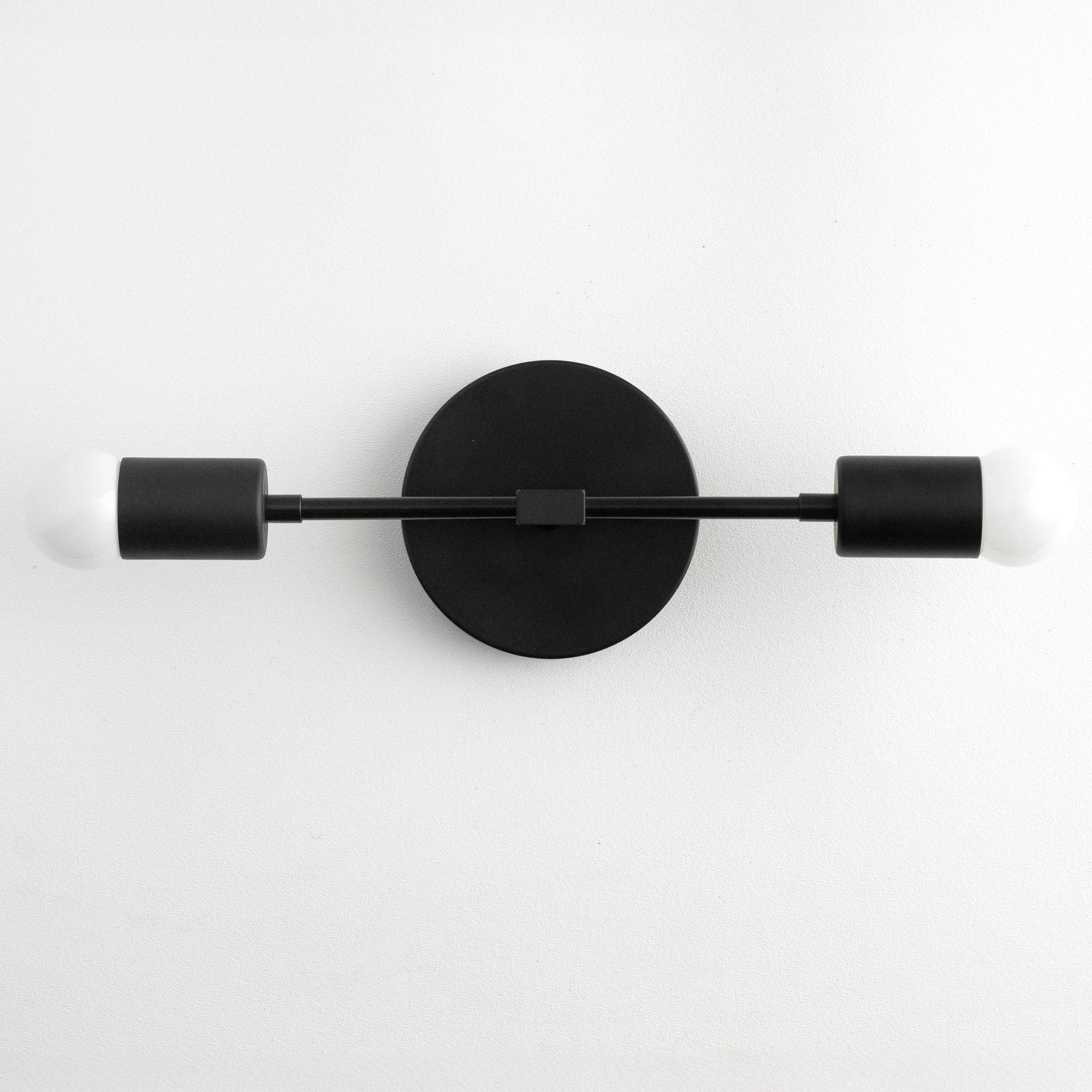 Mid-century modern two-bulb black vanity light with round backplate and bare bulbs. - VANITY LIGHT MODEL NO. 5563