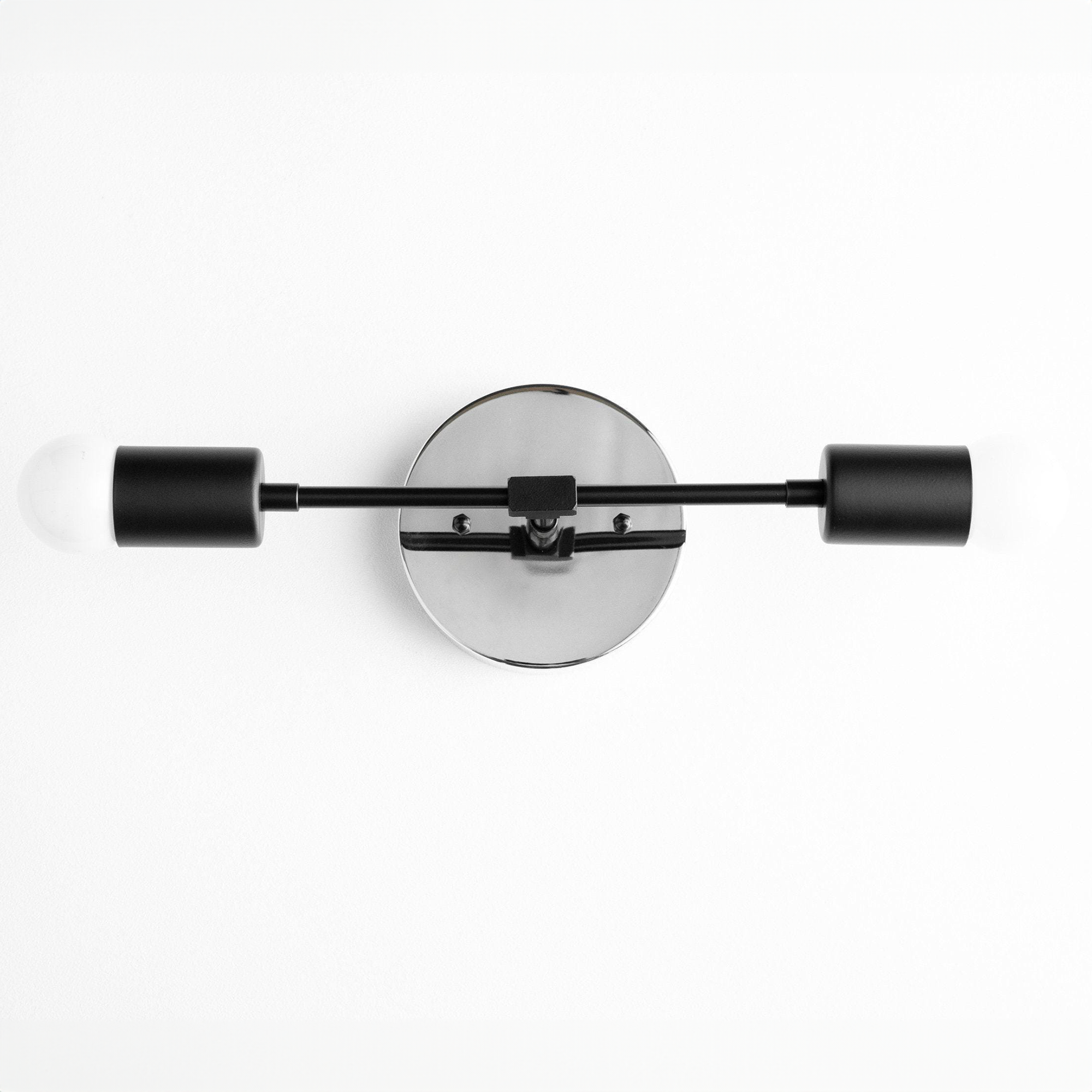 Mid-century modern black two-bulb vanity light with round backplate and cylindrical shades. - VANITY LIGHT MODEL NO. 5563