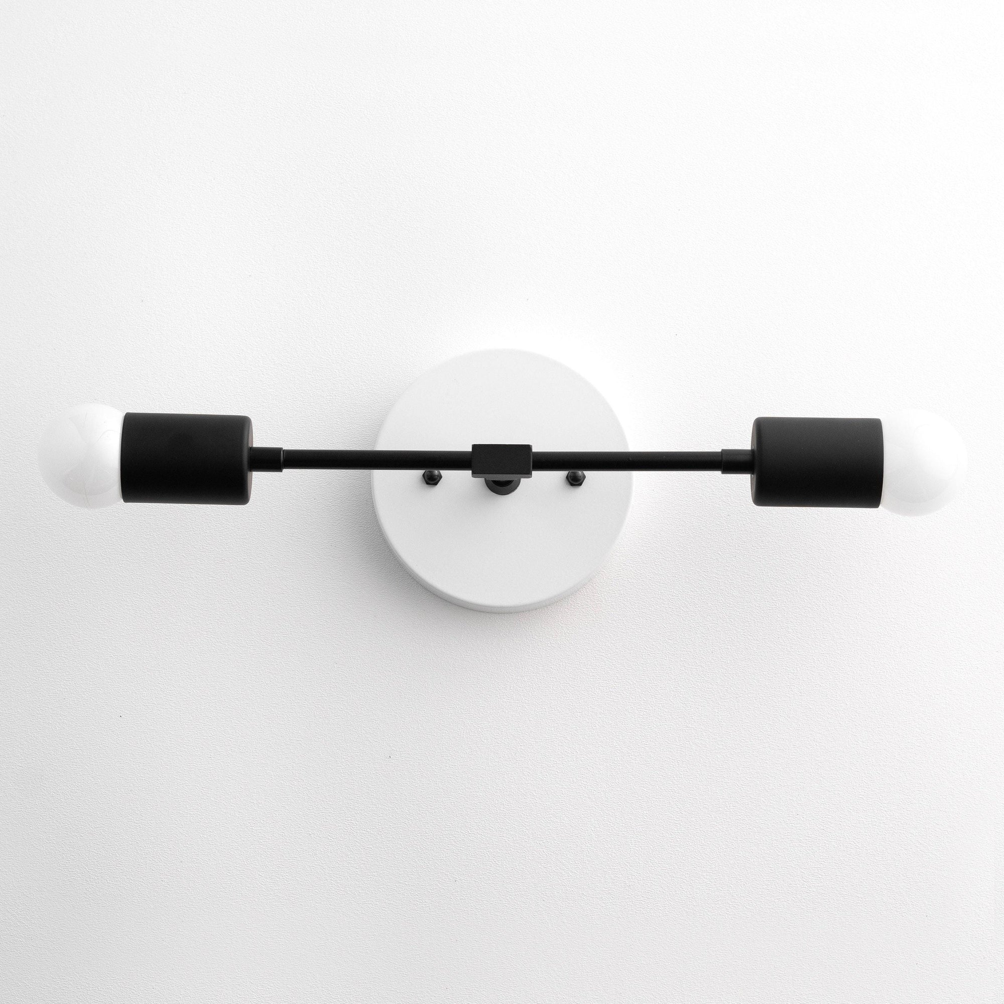 Mid-century modern two-bulb black vanity light with cylindrical shades and round wall mount. - VANITY LIGHT MODEL NO. 5563