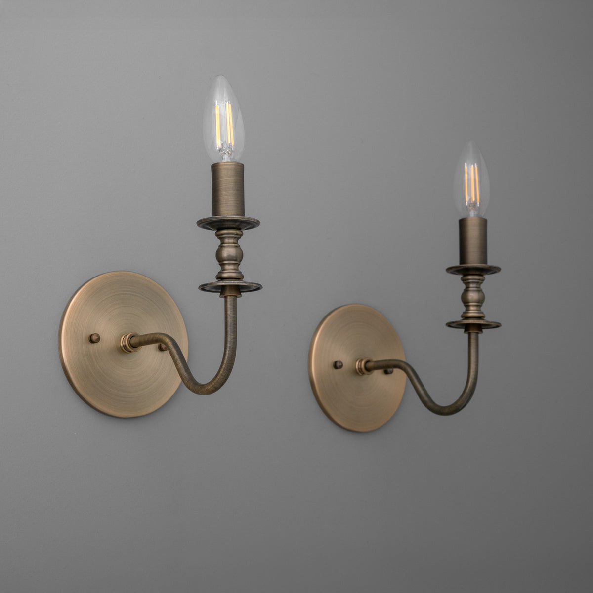 Antique brass metal wall sconces with candle-style bulb holders and round mounting plates. - SCONCE MODEL NO. 9915