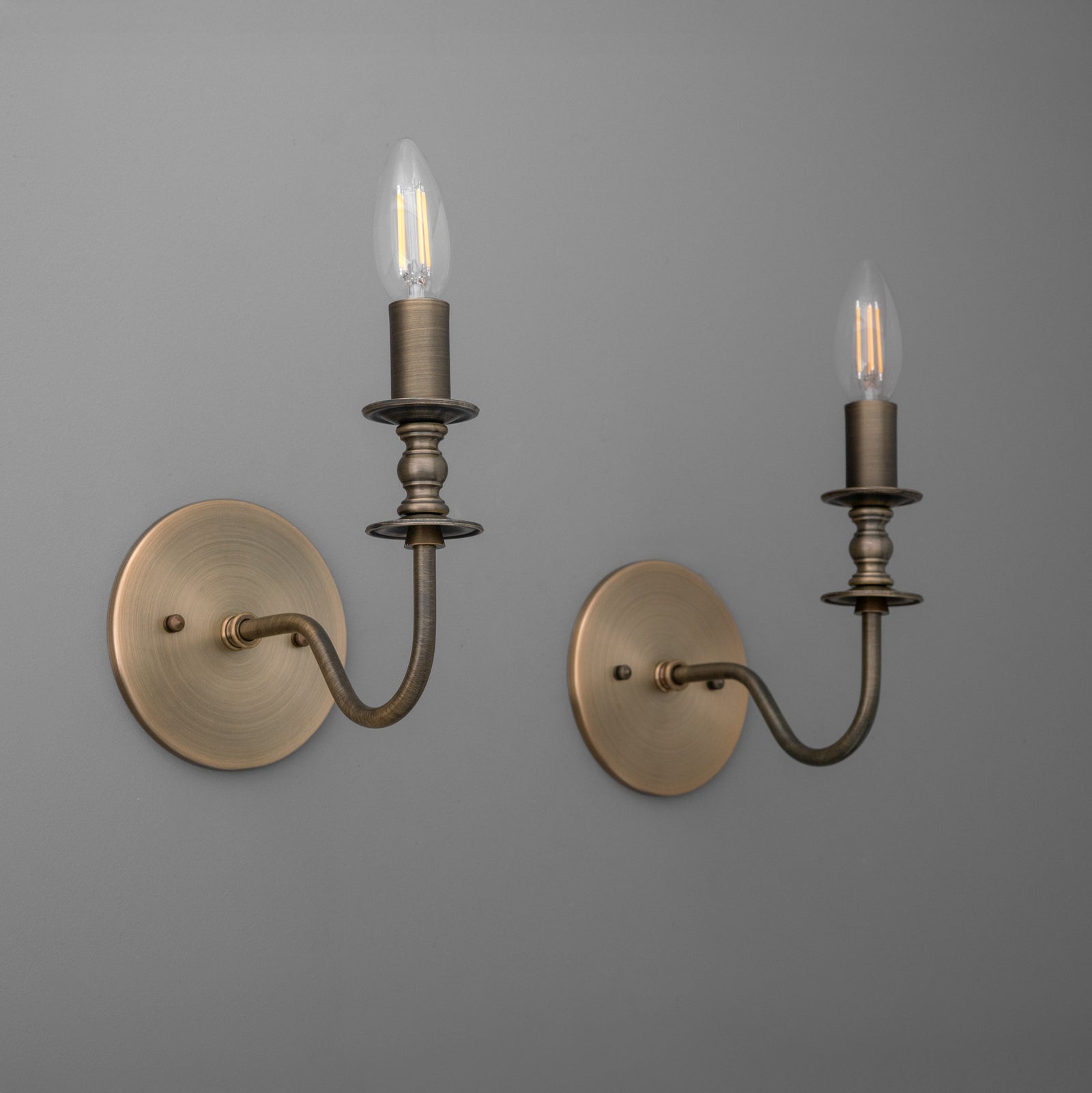 Antique brass metal wall sconces with candle-style bulb holders and round mounting plates. - SCONCE MODEL NO. 9915