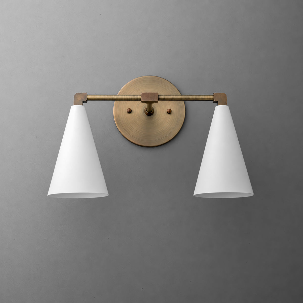Two-light vanity light in Antique Brass with White cone shades on a straight arm and a round wall plate. - VANITY LIGHT MODEL NO. 1184