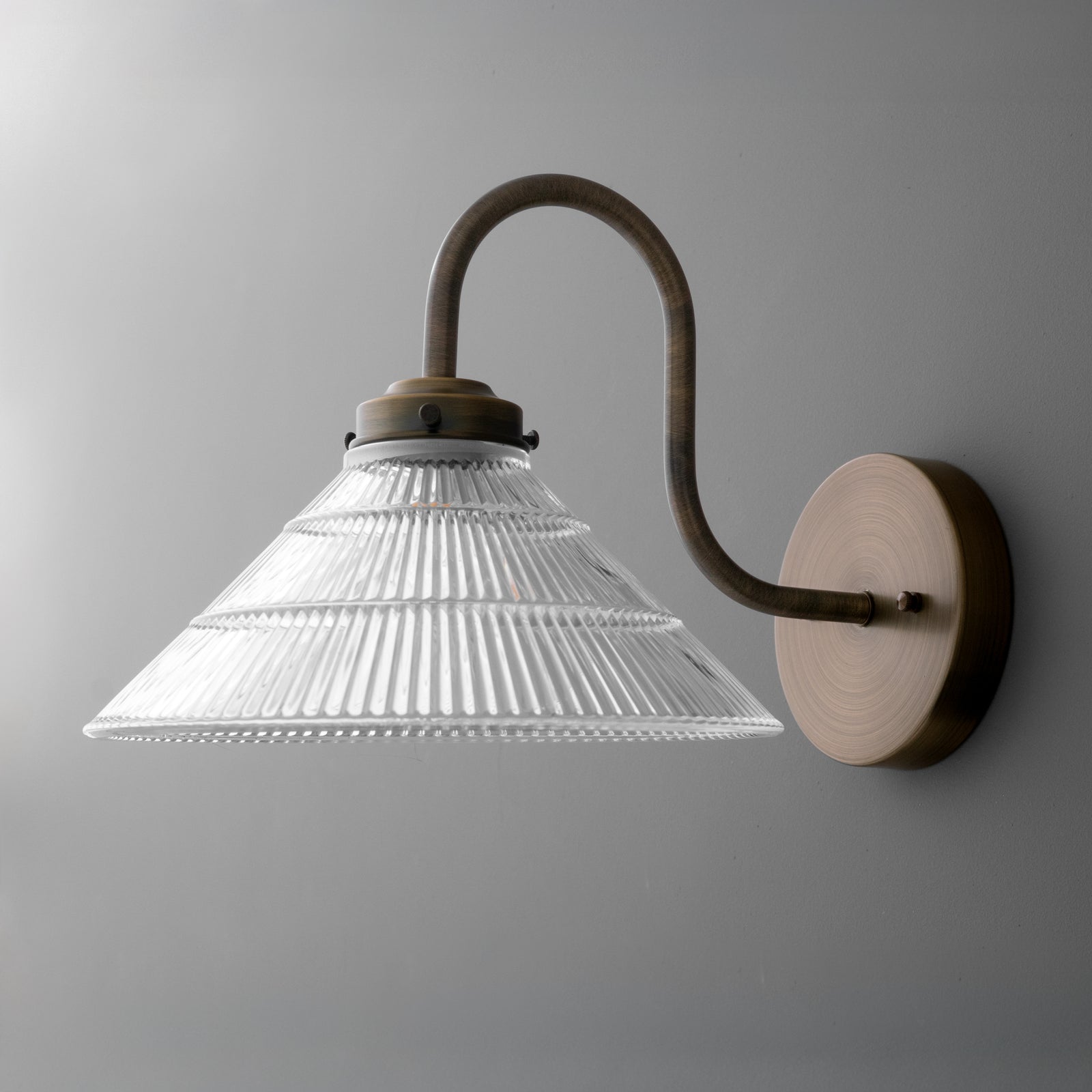 Wall-mounted sconce with clear ribbed glass shade and curved bronze metal arm on round base. - SCONCE MODEL NO. 6263