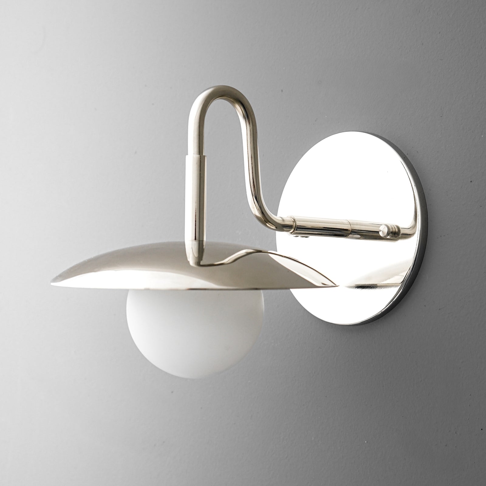 Polished chrome sconce with a curved arm, flat wide shade, and frosted globe bulb. - SCONCE MODEL NO. 1078