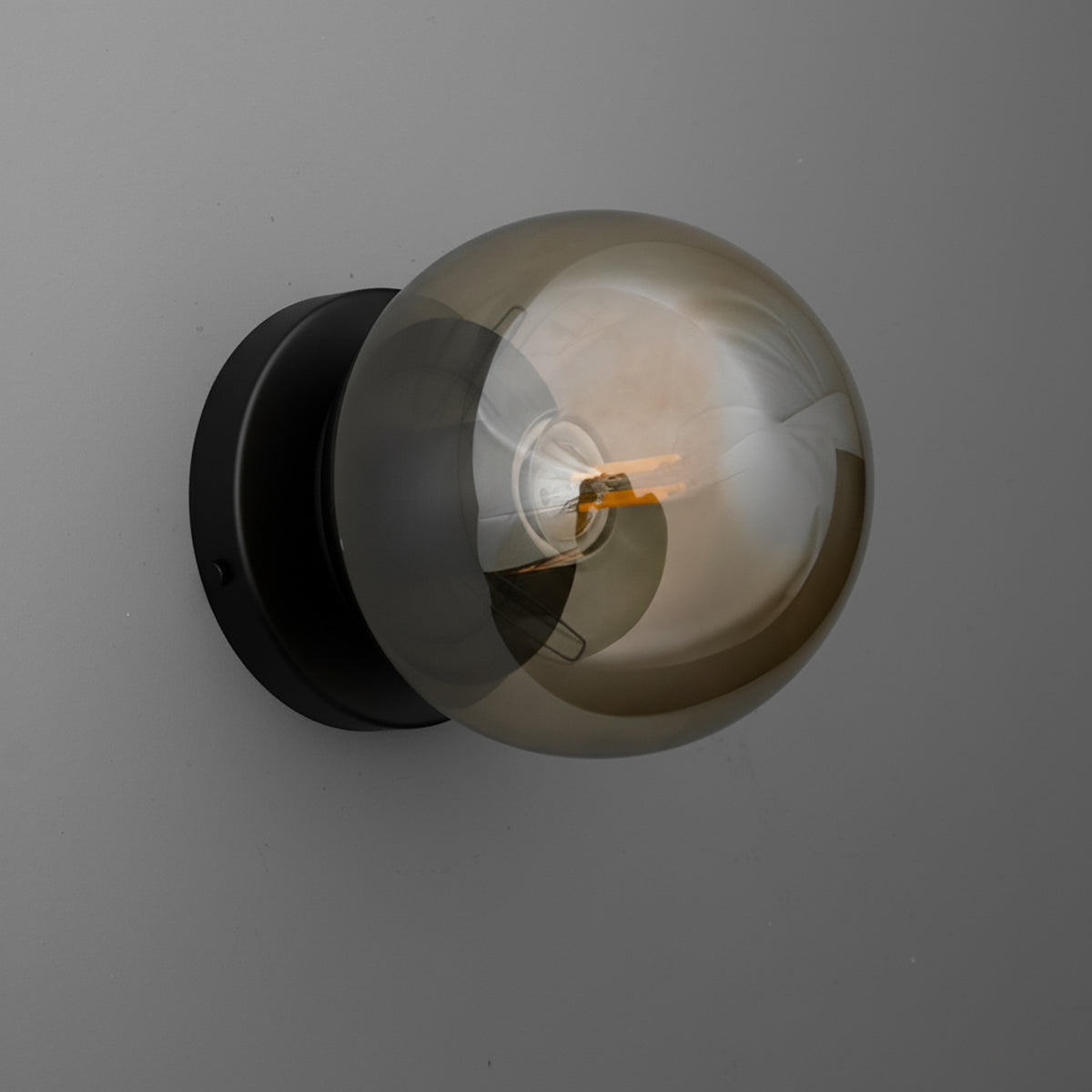 Wall sconce with black circular base and large smoky glass globe shade surrounding filament bulb. - SCONCE MODEL NO. 1030