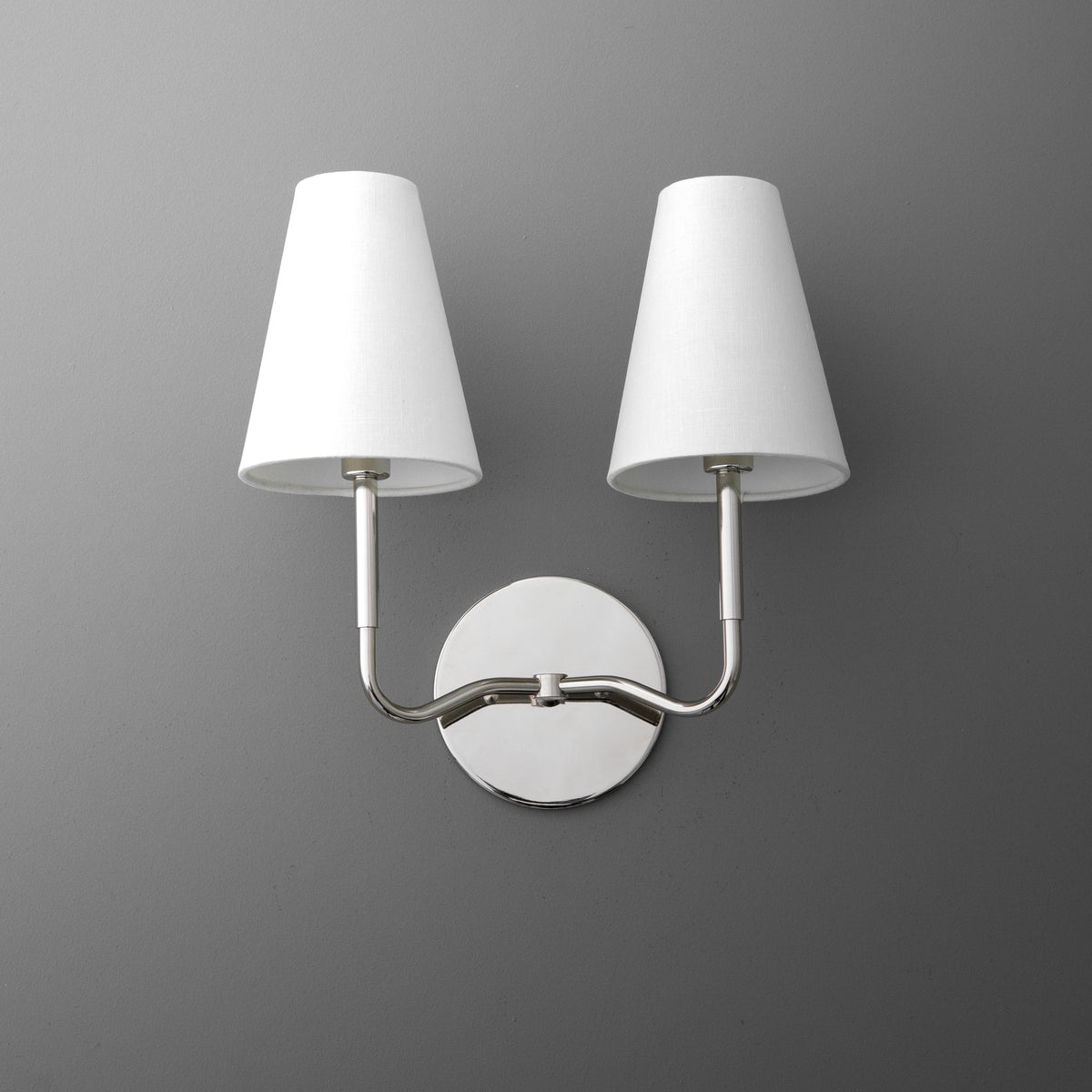 Two-bulb wall sconce with brushed metal arms and white tapered fabric shades on round metal base. - SCONCE MODEL NO. 9045