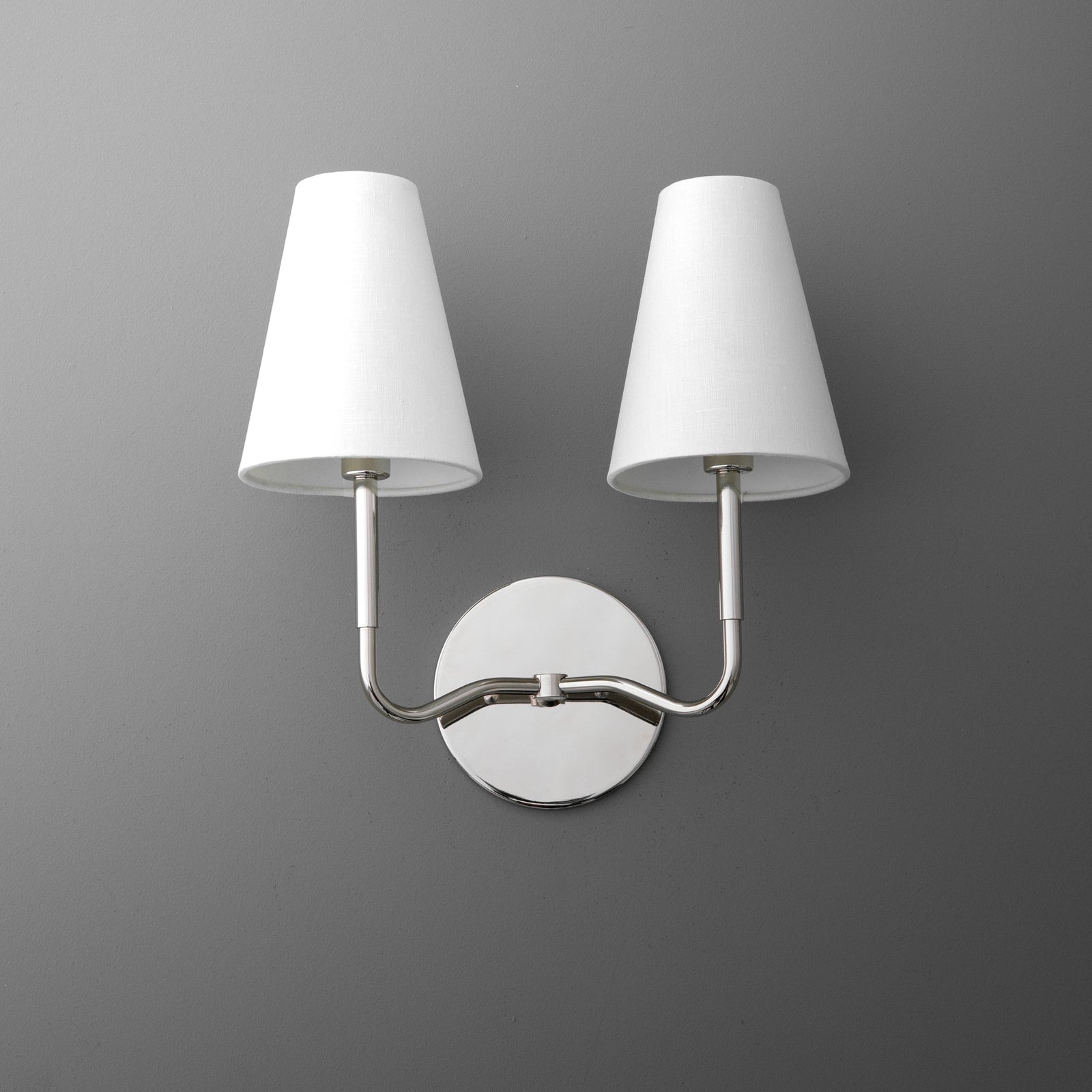 Two-bulb wall sconce with brushed metal arms and white tapered fabric shades on round metal base. - SCONCE MODEL NO. 9045