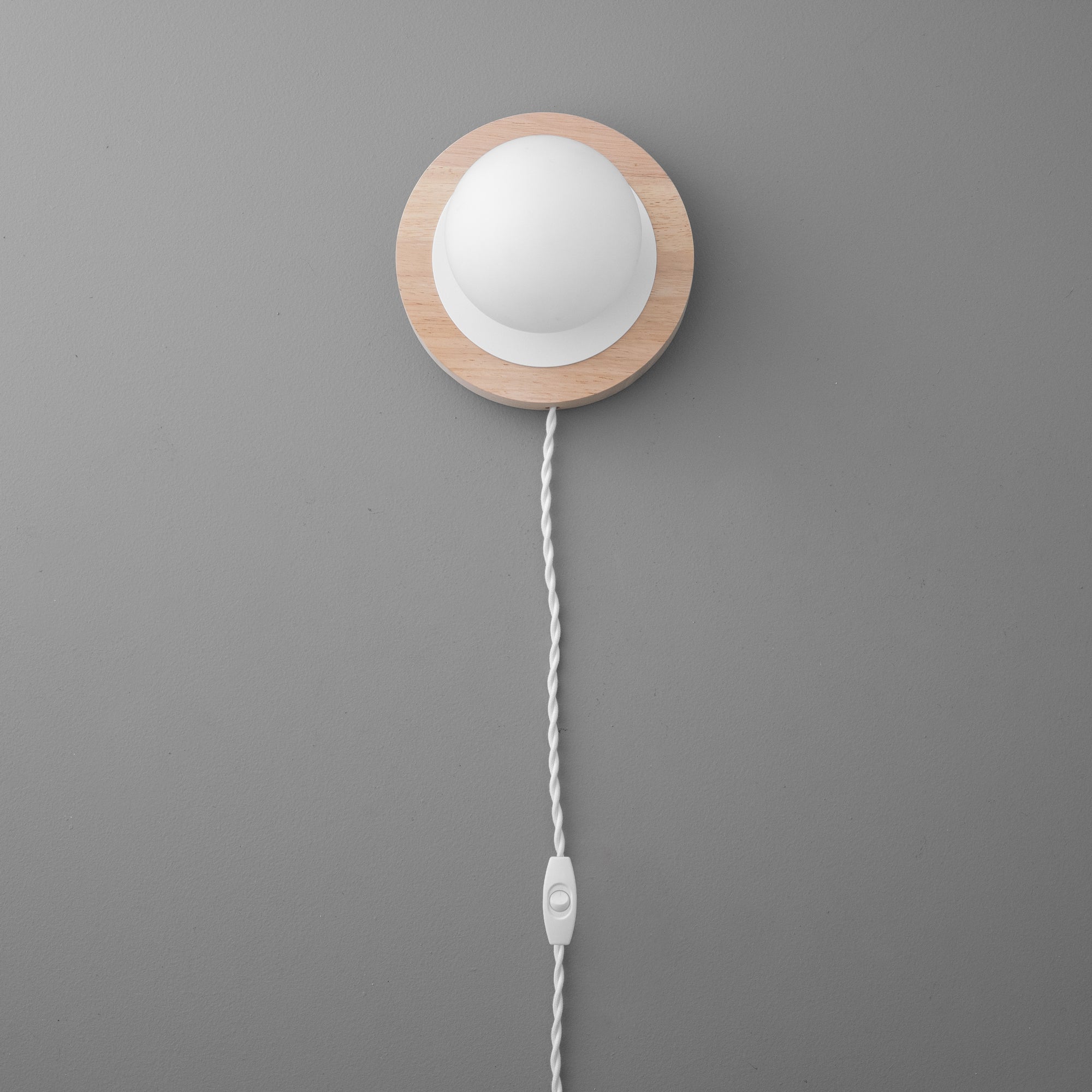 Wall sconce with round white frosted globe and natural wood backplate, white twisted fabric cord with inline switch. - SCONCE MODEL NO. 6154