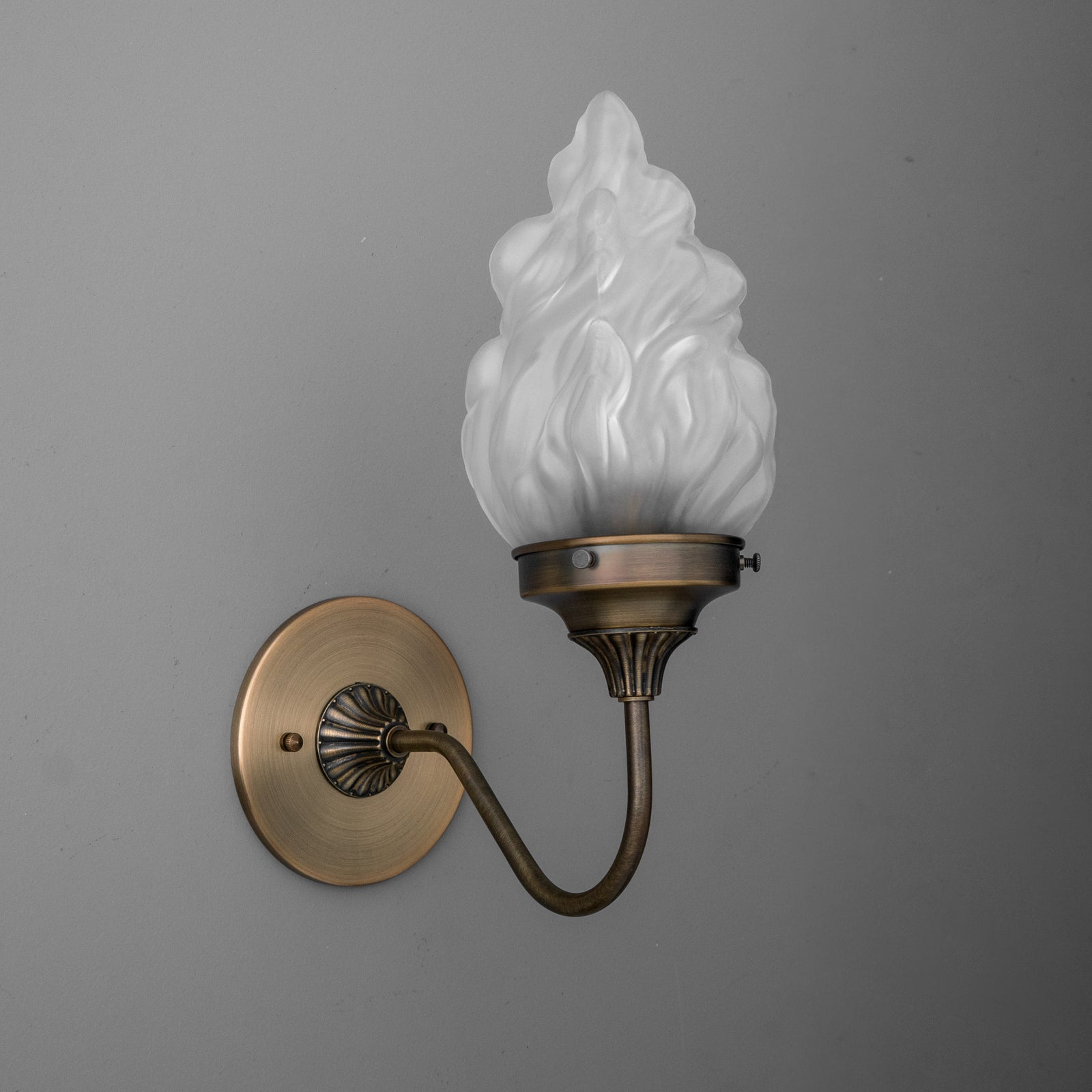 Antique brass wall sconce with curved arm and frosted glass flame-shaped shade. - SCONCE MODEL NO. 1024