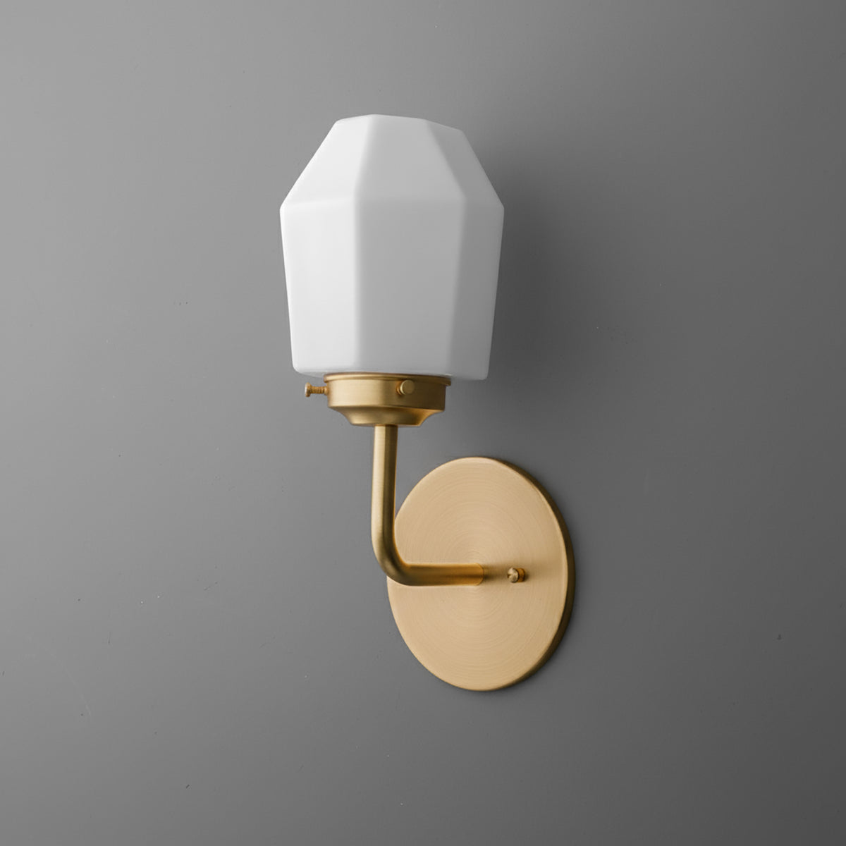 Matte gold metal wall sconce with oval backplate and faceted white glass shade. - SCONCE MODEL NO. 1062