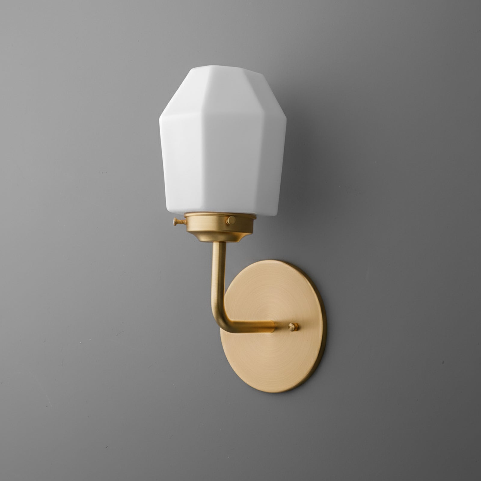 Matte gold metal wall sconce with oval backplate and faceted white glass shade. - SCONCE MODEL NO. 1062