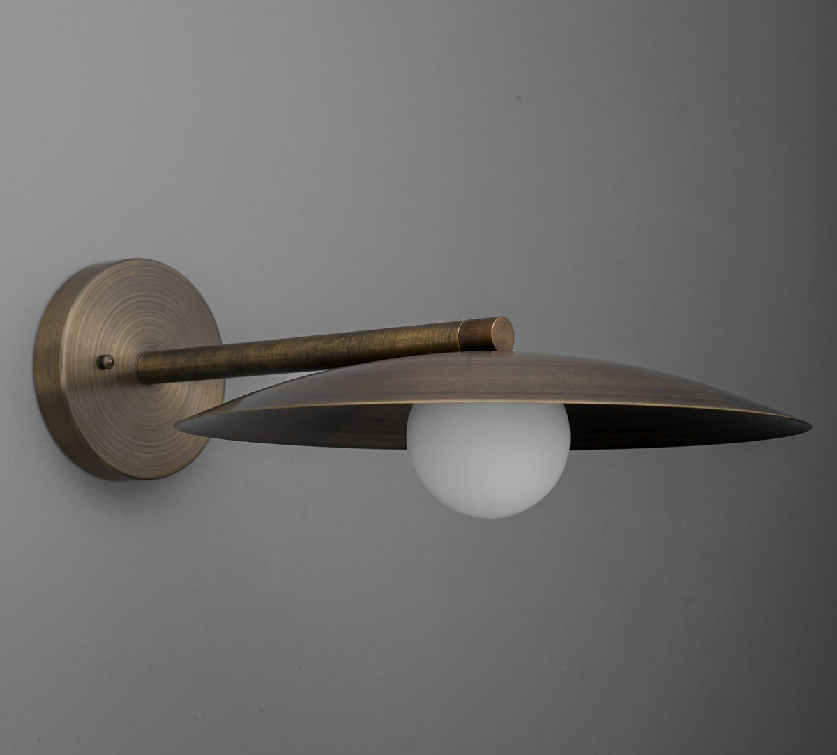 Sconce in Antique Brass with a wide shallow dish shade over an opal glass globe, on a straight arm from a round wall plate. - SCONCE MODEL NO. 1076