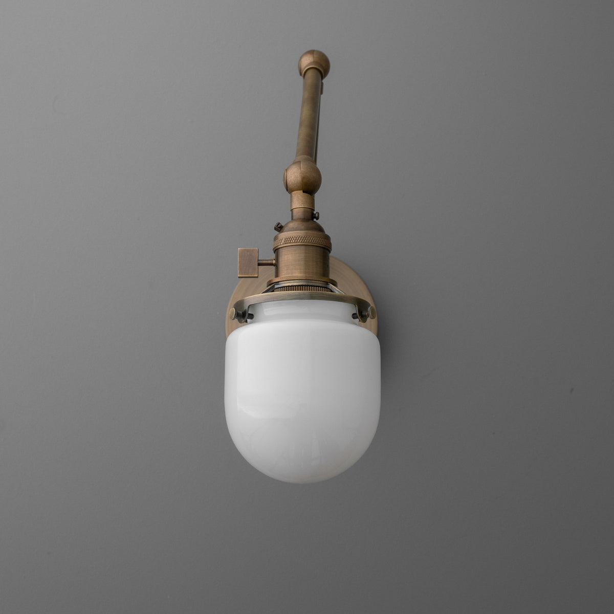Wall-mounted bronze sconce with a single round white glass globe shade and vintage-inspired metal details. - SCONCE MODEL NO. 7575