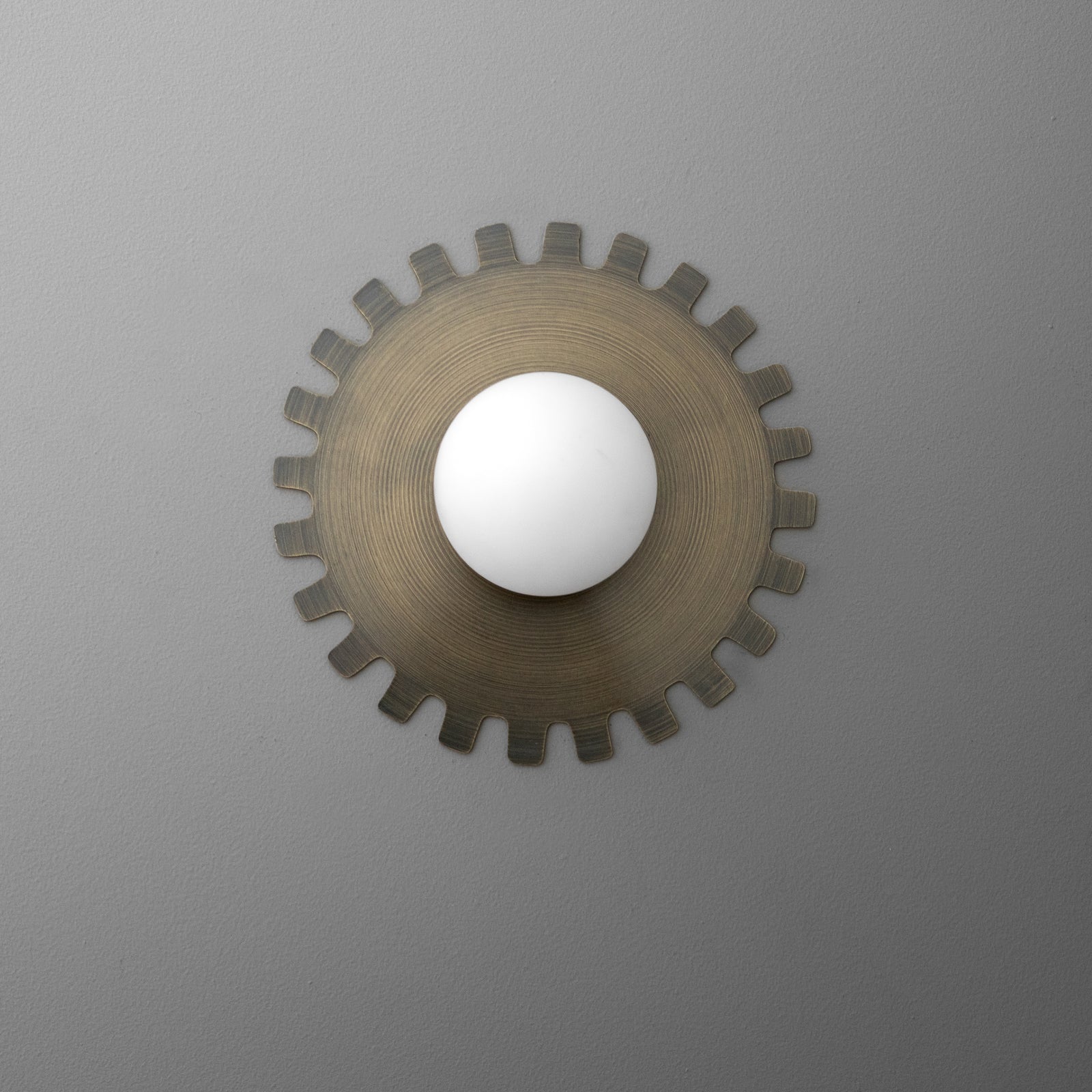 Wall sconce with round frosted glass bulb cover and bronze gear-shaped metal backplate. - SCONCE MODEL NO. 1123