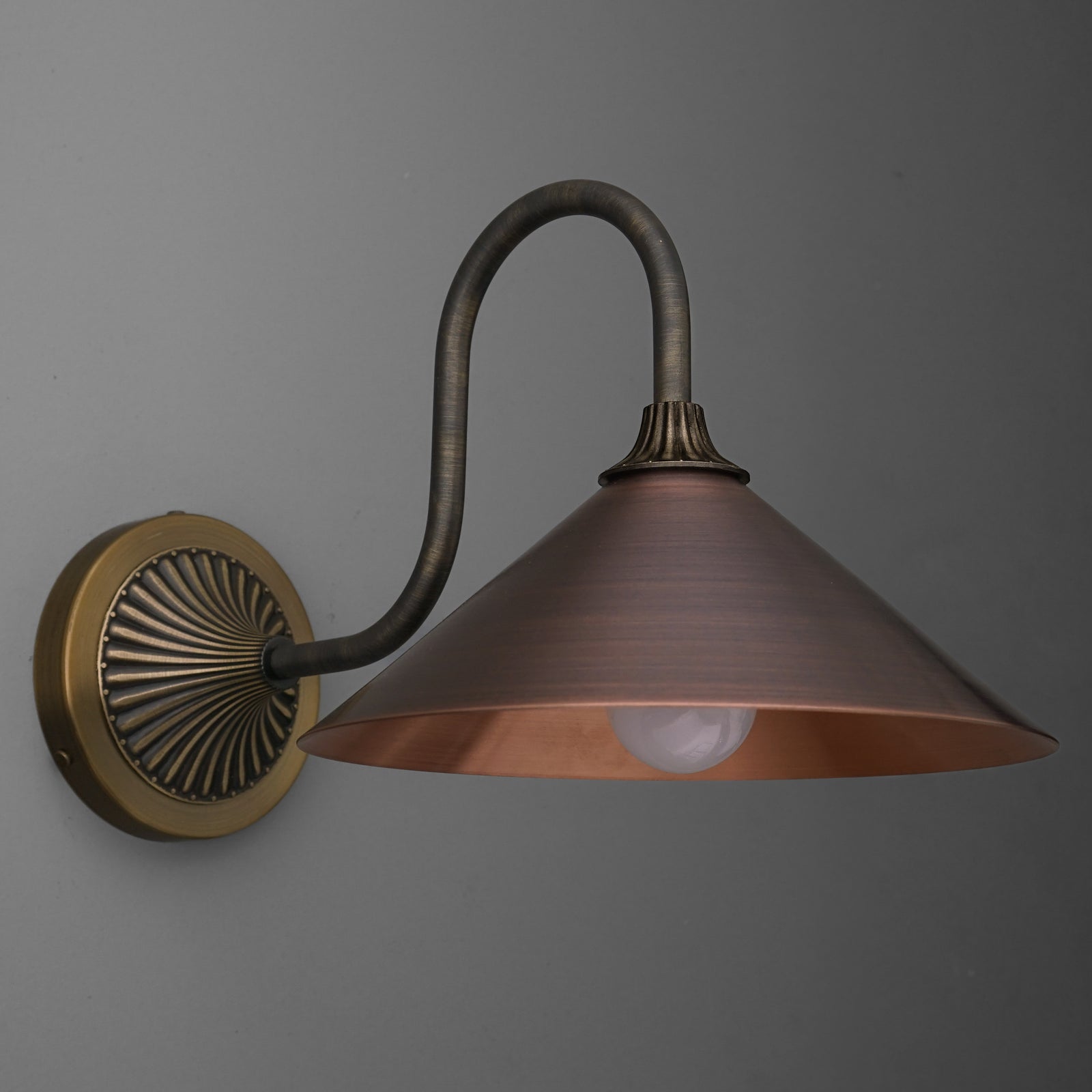 Wall-mounted single-bulb sconce with curved dark metal arm and wide conical copper shade. - SCONCE MODEL NO. 1055
