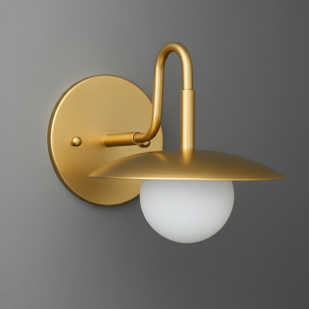 Matte gold wall sconce with round backplate, curved arm, and frosted white globe shade. - SCONCE MODEL NO. 1078