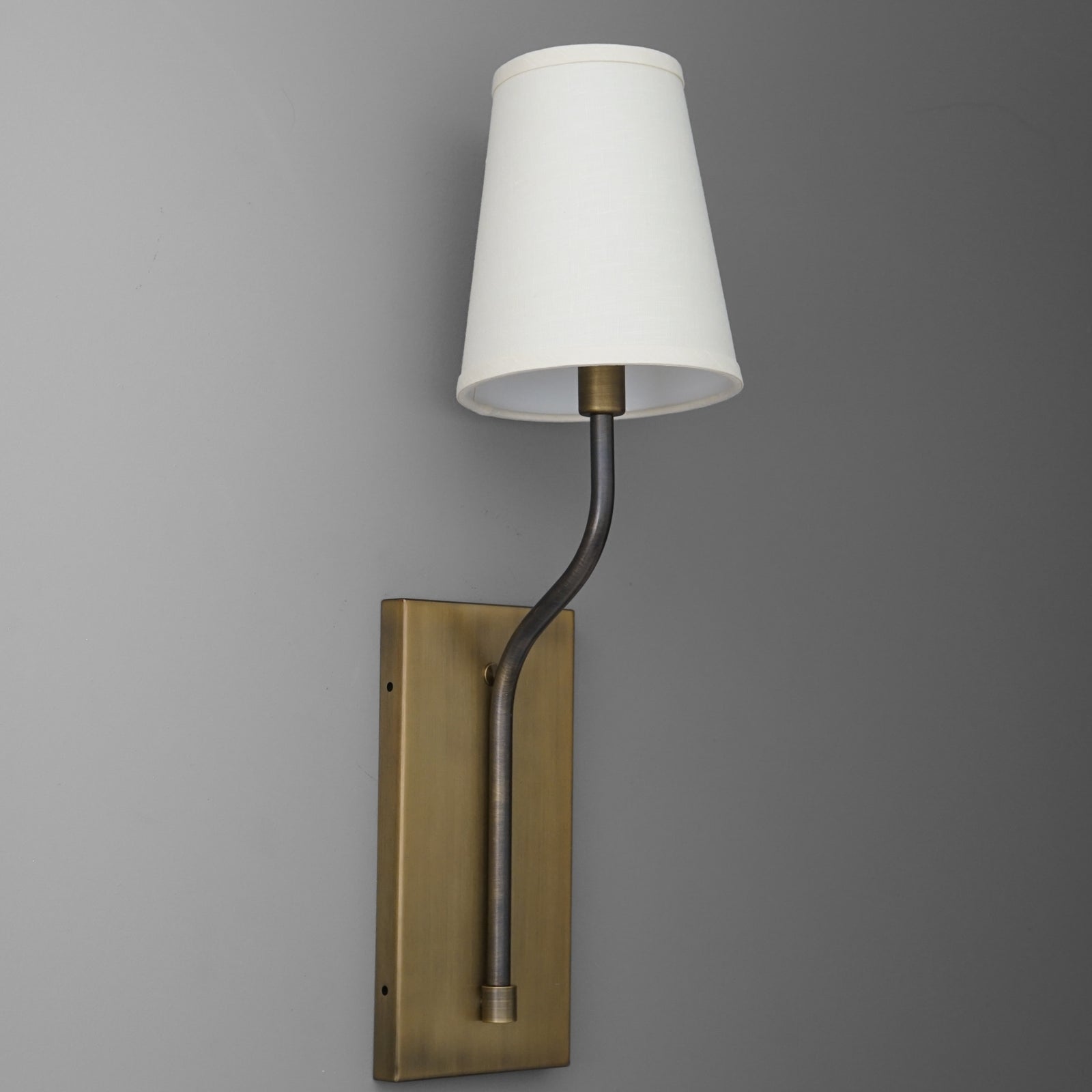 Wall sconce with brushed brass rectangular base, curved black arm, and white tapered fabric shade. - SCONCE MODEL NO. 9714
