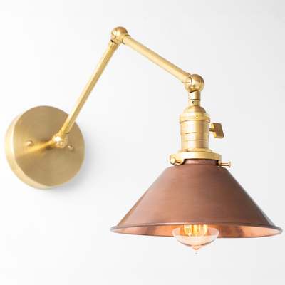 Adjustable wall sconce with antique brass arm and conical copper shade, vintage Edison bulb visible. - SCONCE MODEL NO. 6668