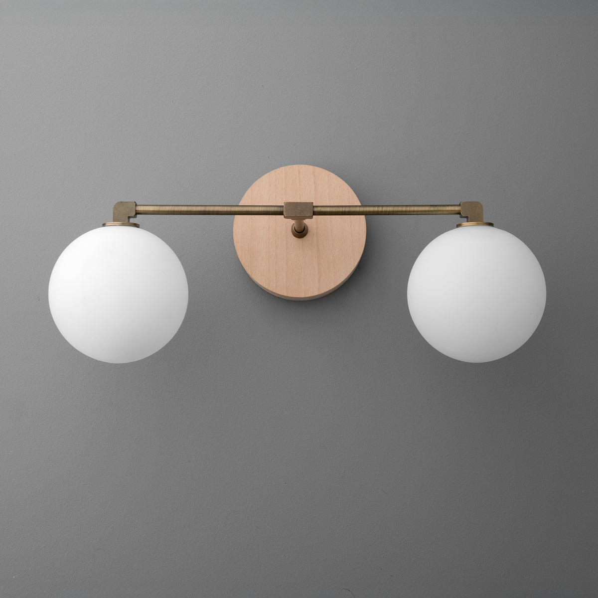 Two-bulb vanity light with round white glass shades and brass arms on a circular wooden base. - VANITY LIGHT MODEL NO. 1151