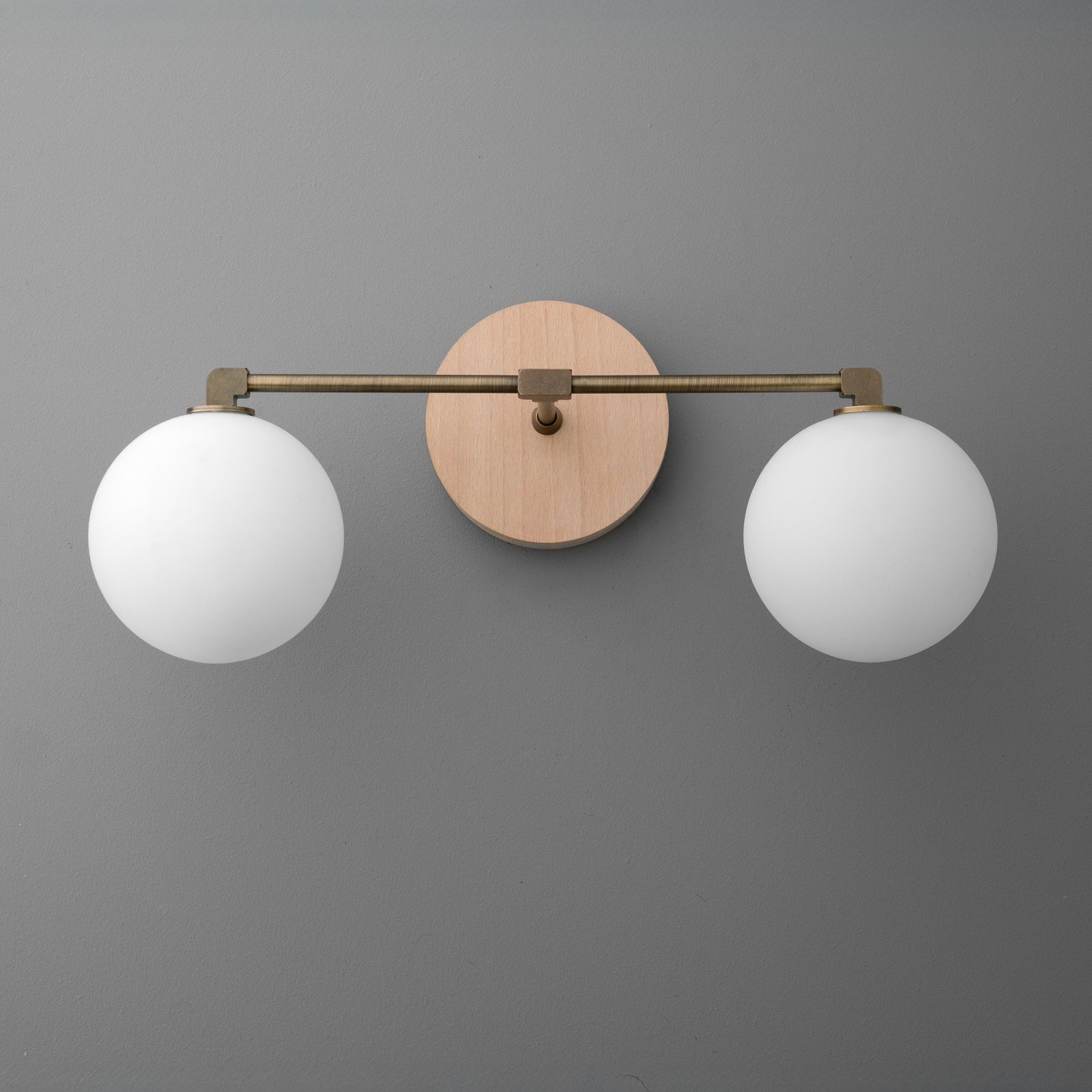 Two-bulb vanity light with round white glass shades and brass arms on a circular wooden base. - VANITY LIGHT MODEL NO. 1151