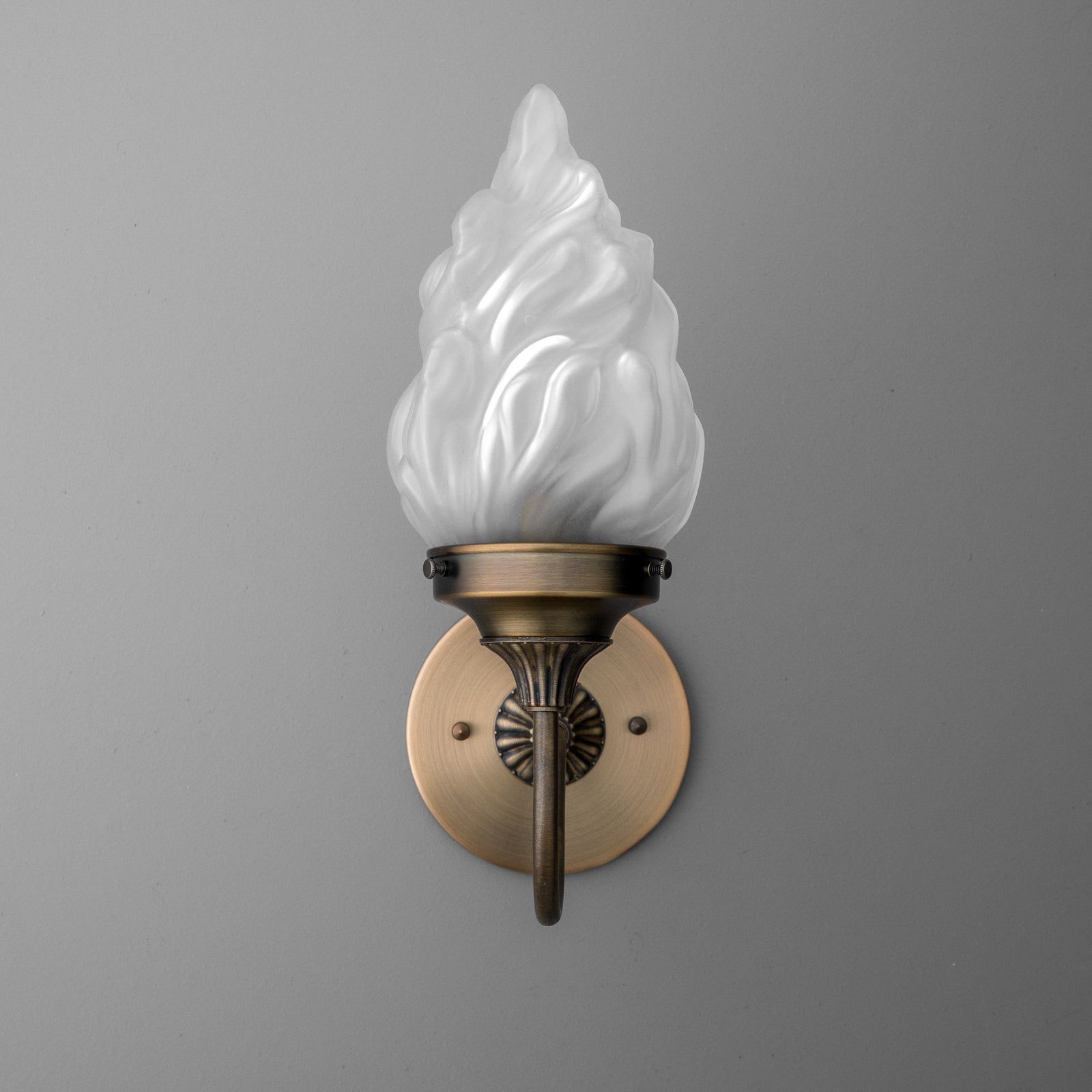 Wall sconce with antique brass finish and frosted glass flame-shaped shade, single bulb design. - SCONCE MODEL NO. 1024