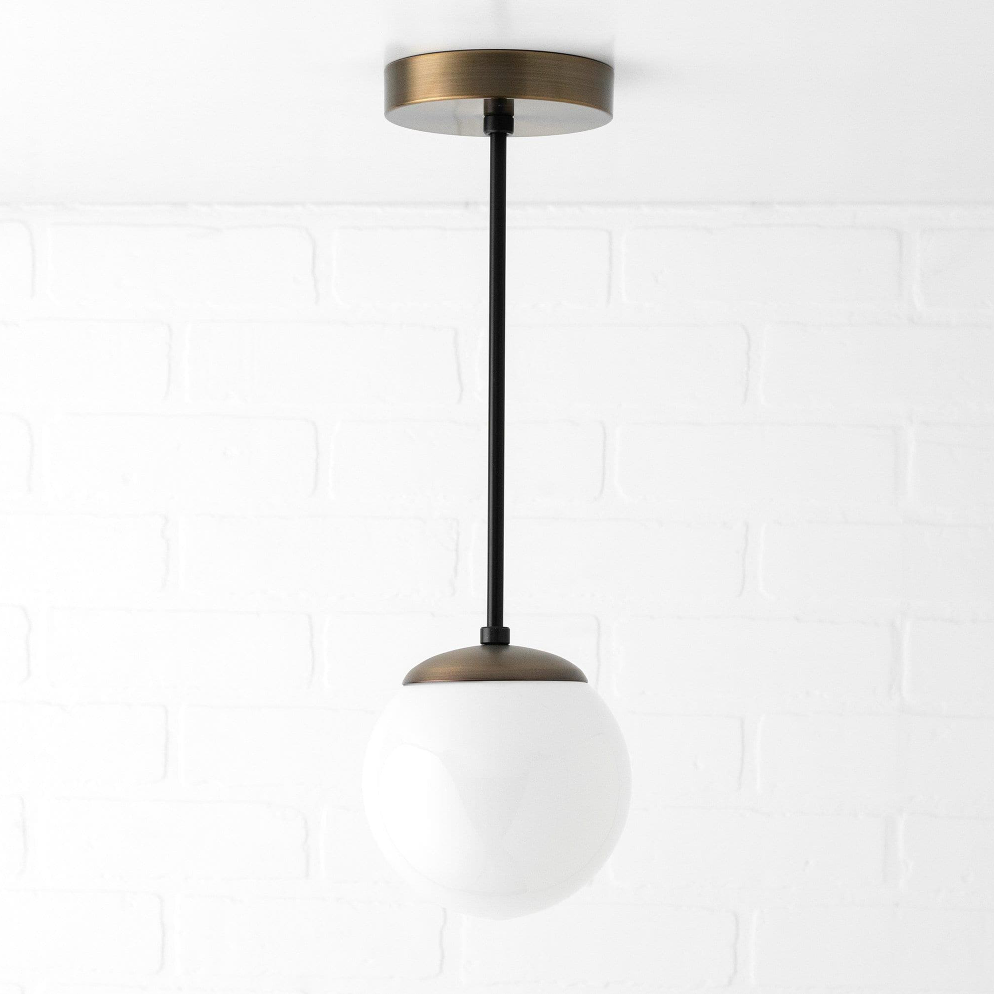 Mid-century modern globe pendant light with raw brass finish and white glass globe shade. - PENDANT MODEL NO. 7056
